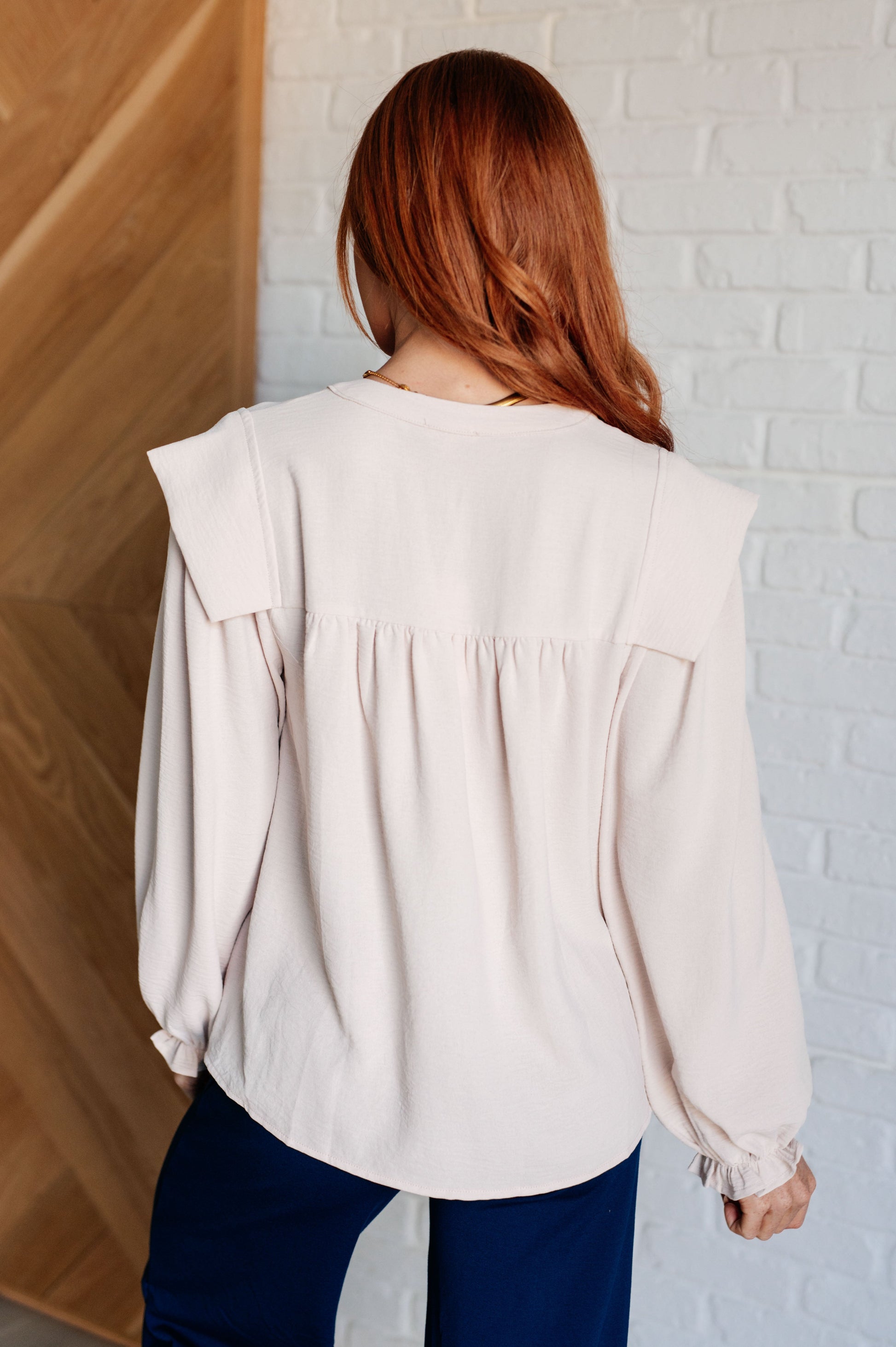 Crinkle woven blouse with a V-neckline, long bishop sleeves, cap shoulders, frilled sleeve cuffs, and gathered details.