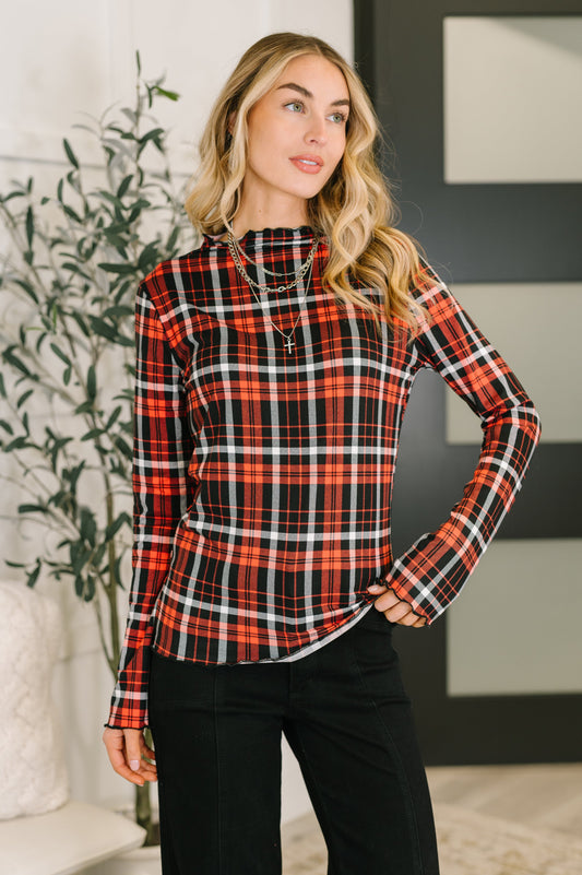 Model wearing Shane Plaid Lettuce Hem Top in red with high neckline and fitted silhouette.