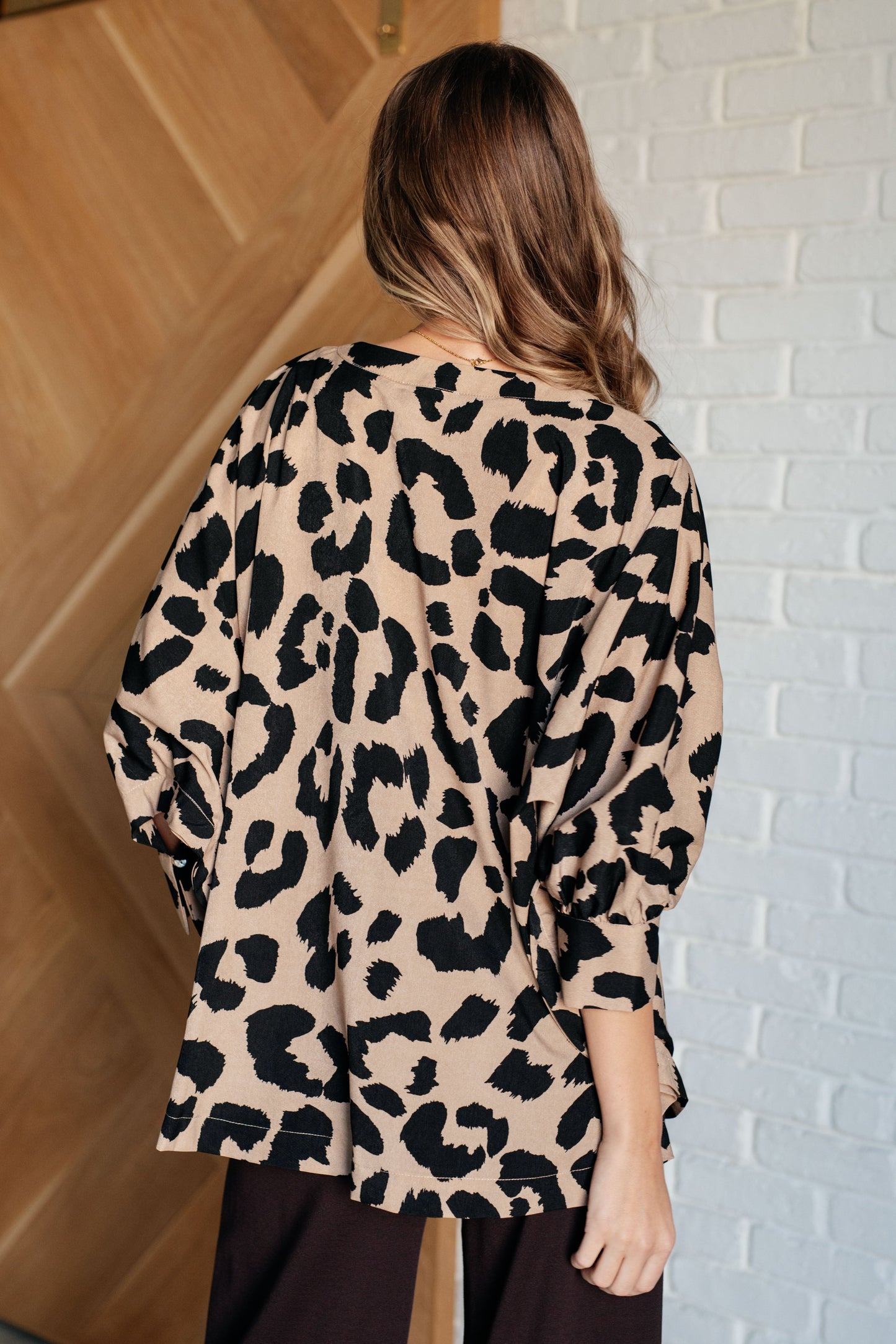 Beige and Black animal print blouse with a V-neckline, batwing sleeves, and a loose, flowing fit. Features banded cuffs with buttons.