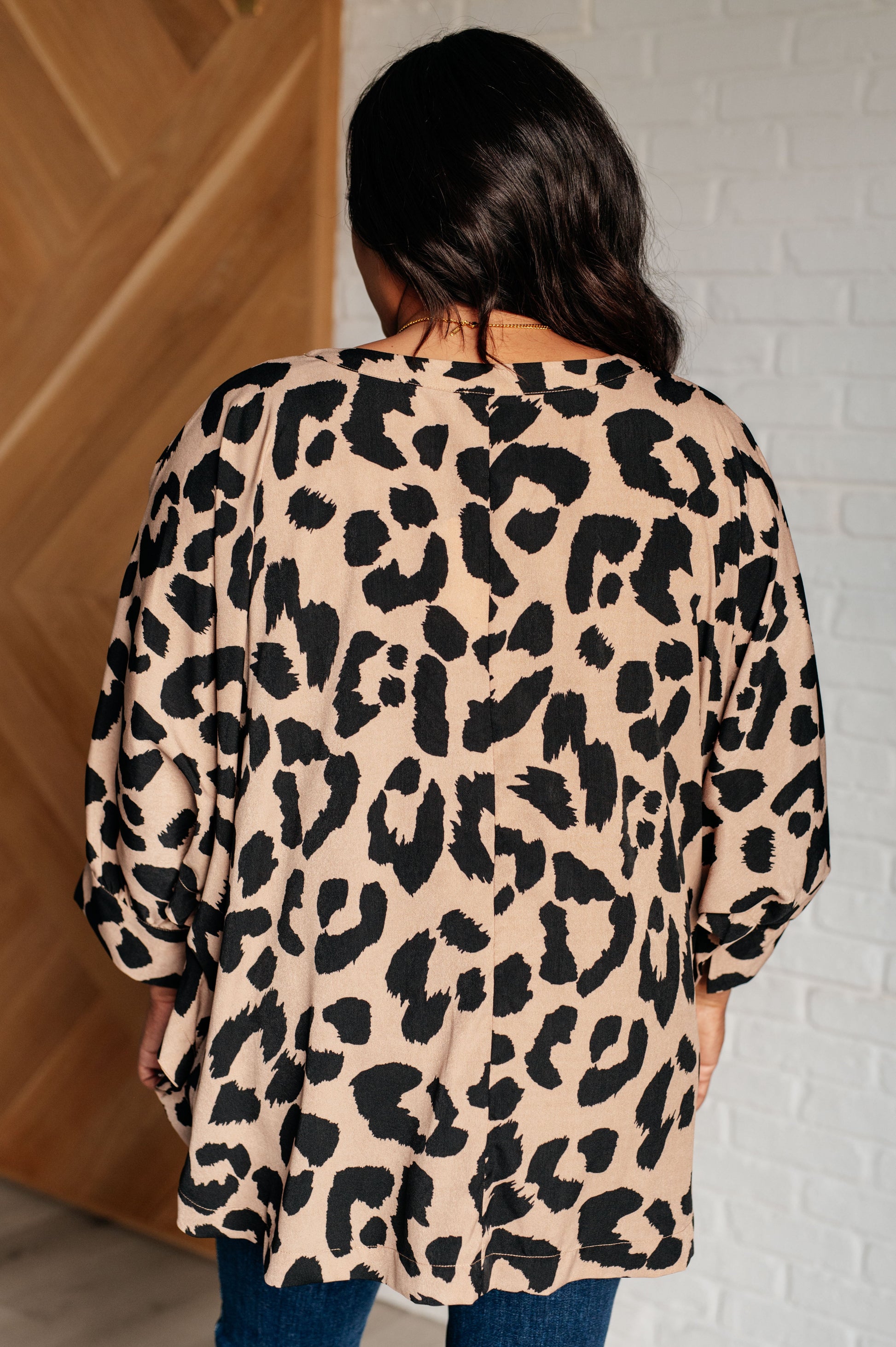 Beige and Black animal print blouse with a V-neckline, batwing sleeves, and a loose, flowing fit. Features banded cuffs with buttons.