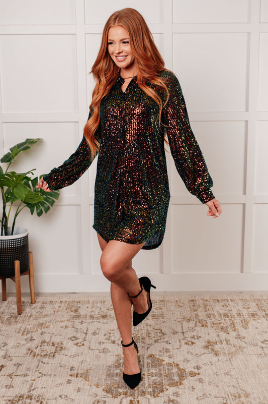 Black and green sequin mesh mini shirt dress with a collared neckline, long sleeves, and button front closure. Fully lined with buttoned cuffs.