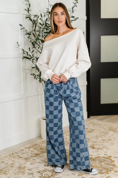 Full body view of model in Marlowe Off Shoulder Top in Bone, styled with checkered jeans and sneakers for a casual streetwear vibe.
