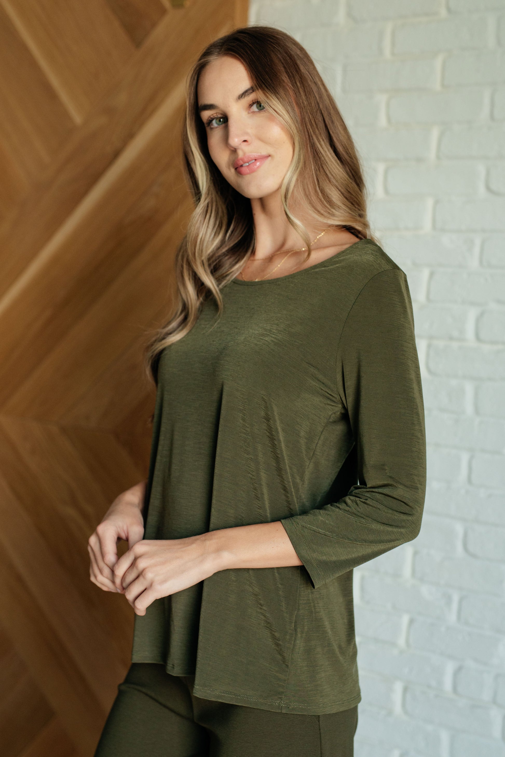 Women's top in olive, featuring a round neckline, 3/4 sleeves, and a flowy wrinkle-resistant design made from lightweight Bulgari fabric.