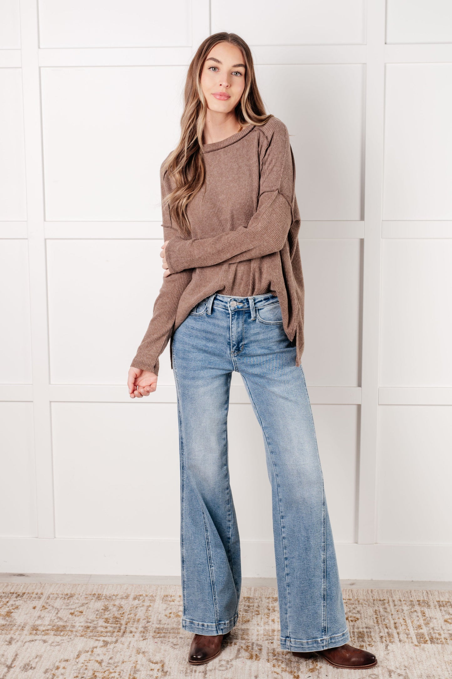 Model wearing Simon Ribbed Hacci Sweater in mocha with side slits and chic exposed seam accents.