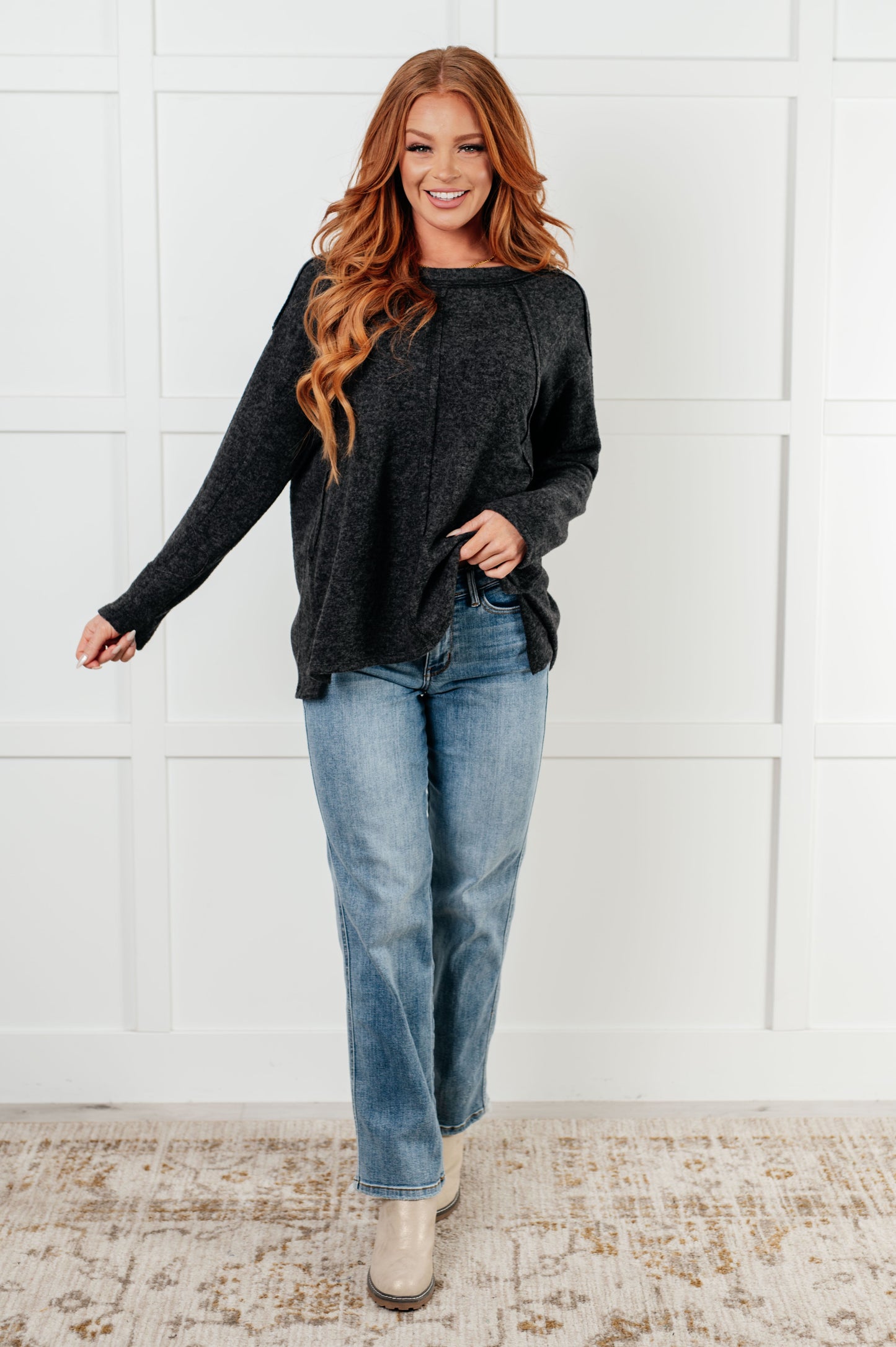 Women's Symmer Brushed Hacci Sweater in Black featuring a round neckline, drop shoulders, stepped hemline, side slits, and raw seams.