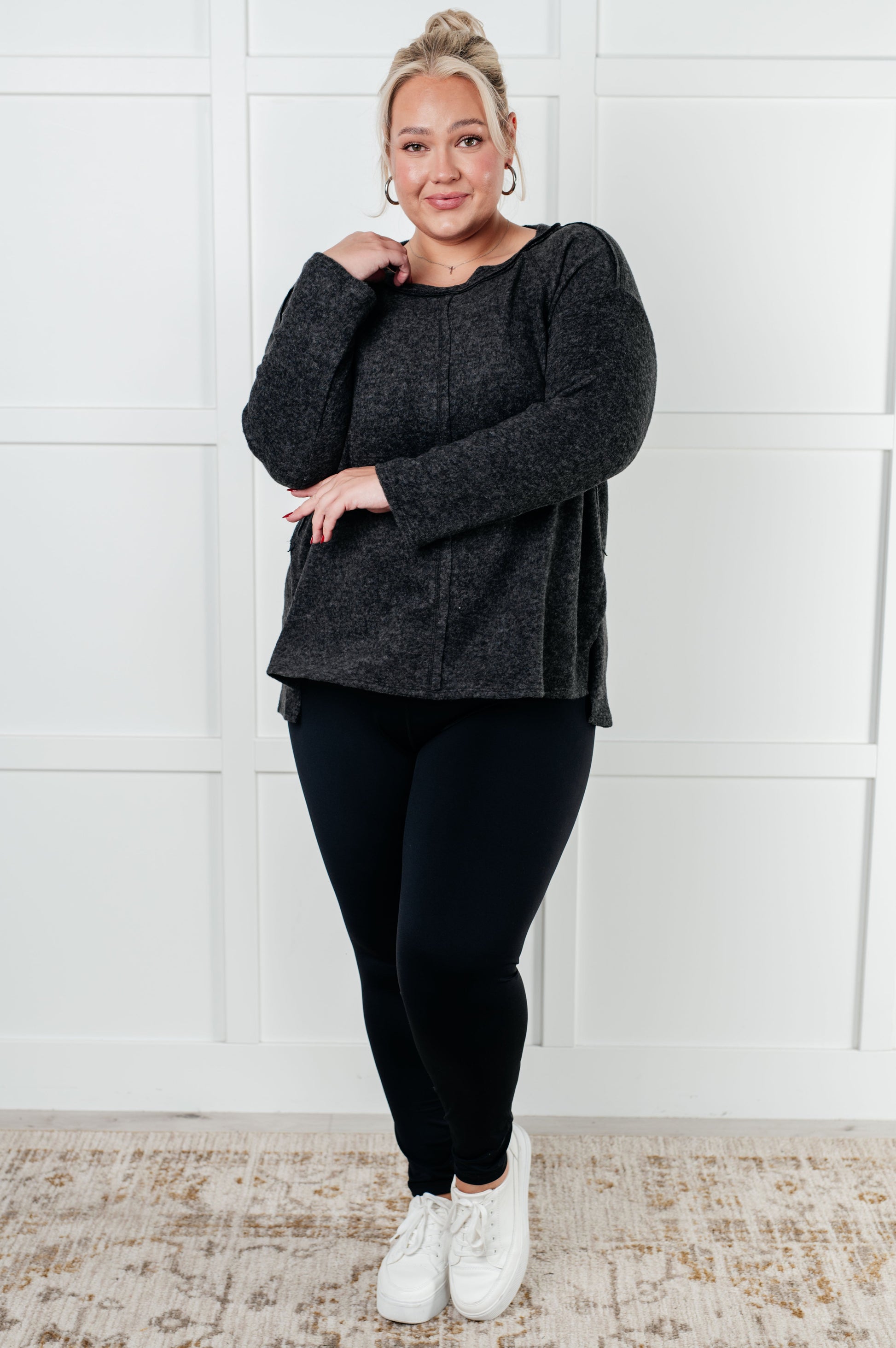 Women's Symmer Brushed Hacci Sweater in Black featuring a round neckline, drop shoulders, stepped hemline, side slits, and raw seams.