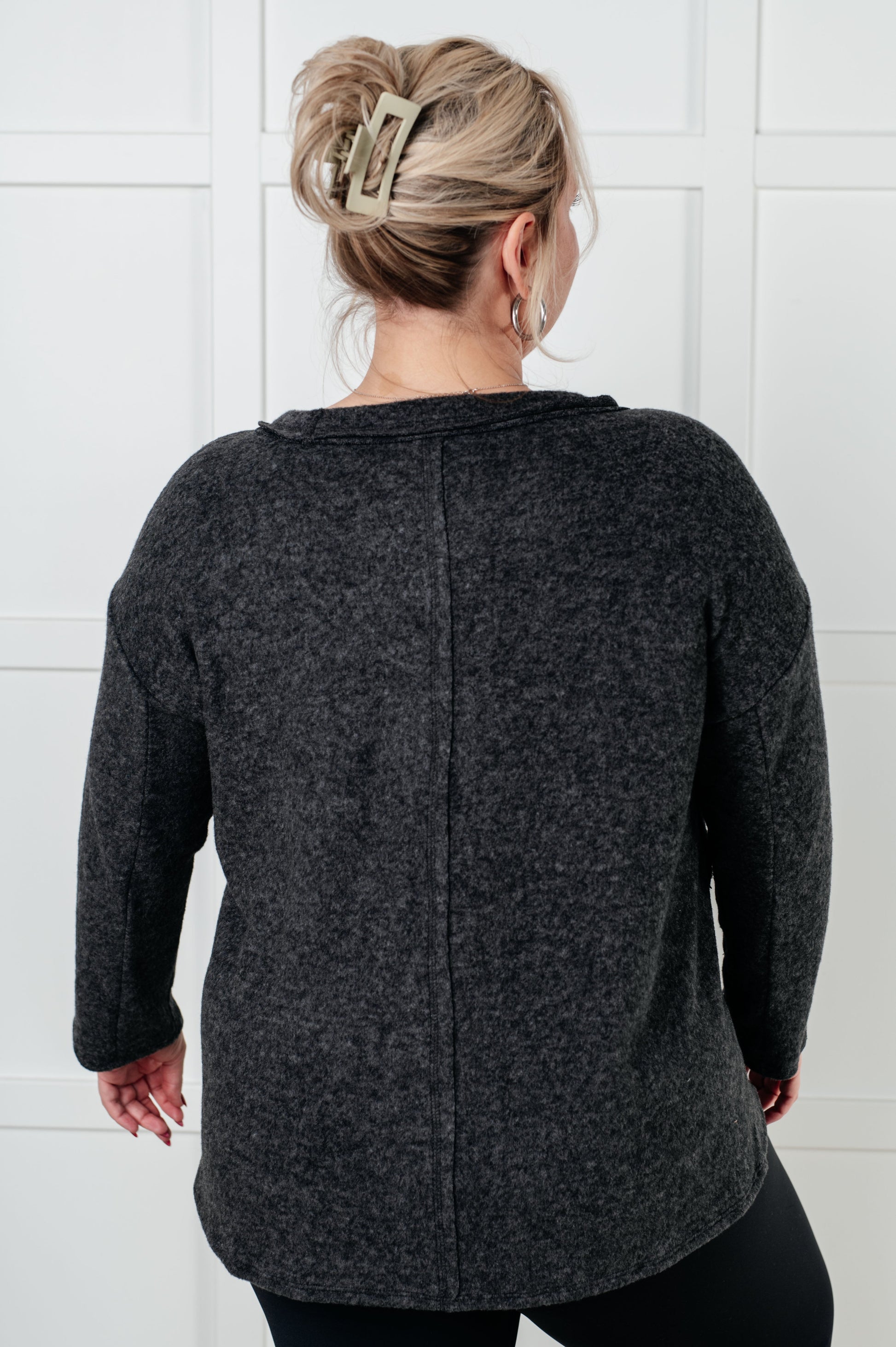 Women's Symmer Brushed Hacci Sweater in Black featuring a round neckline, drop shoulders, stepped hemline, side slits, and raw seams.