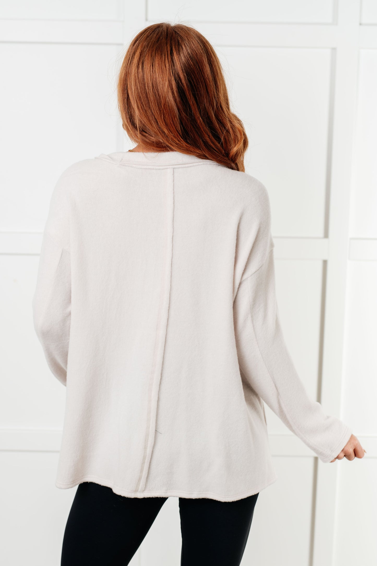 Women's Brushed Hacci Sweater in Sand Beige featuring a round neckline, drop shoulders, stepped hemline, side slits, and raw seams. 