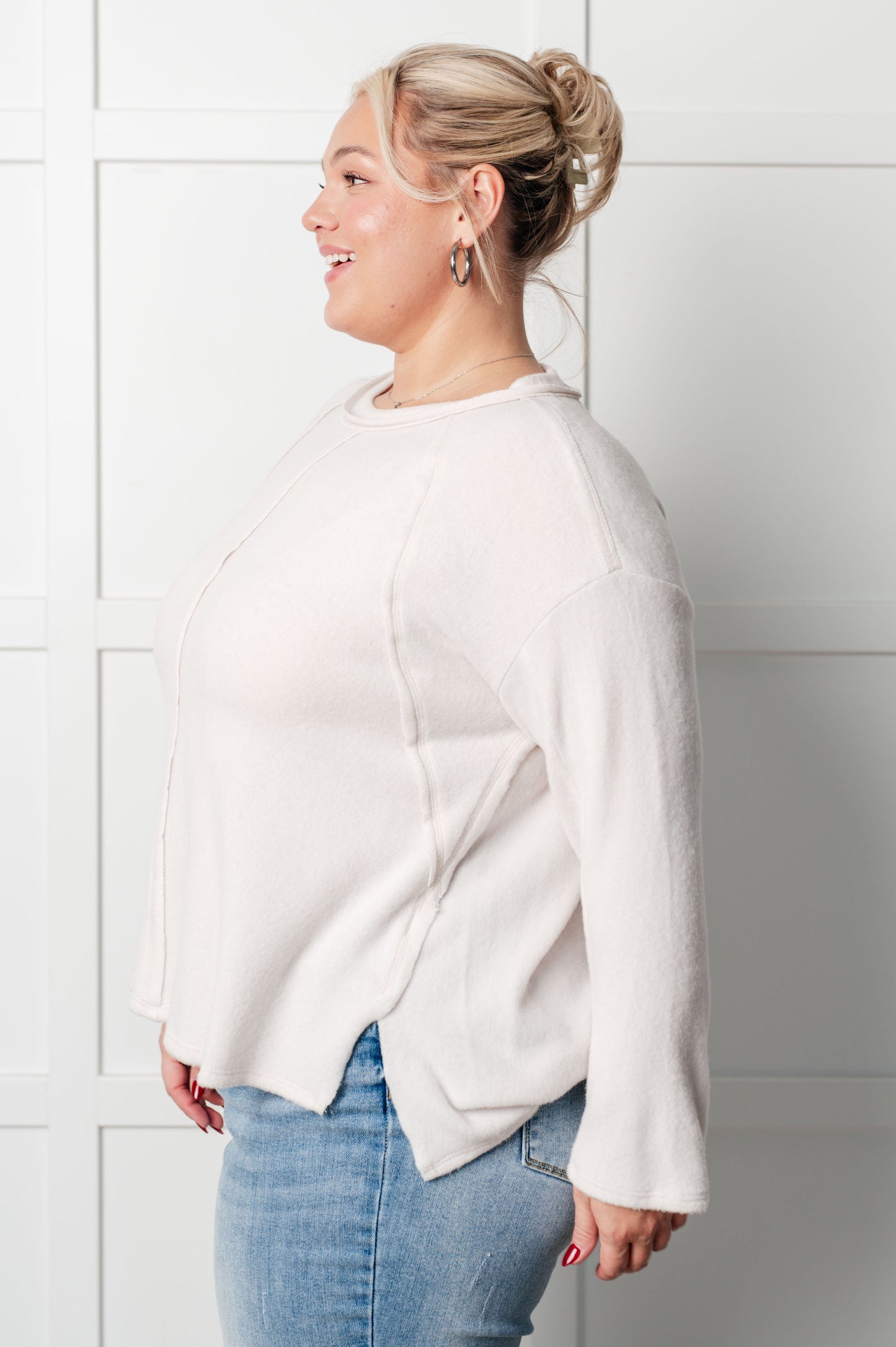 Women's Brushed Hacci Sweater in Sand Beige featuring a round neckline, drop shoulders, stepped hemline, side slits, and raw seams. 