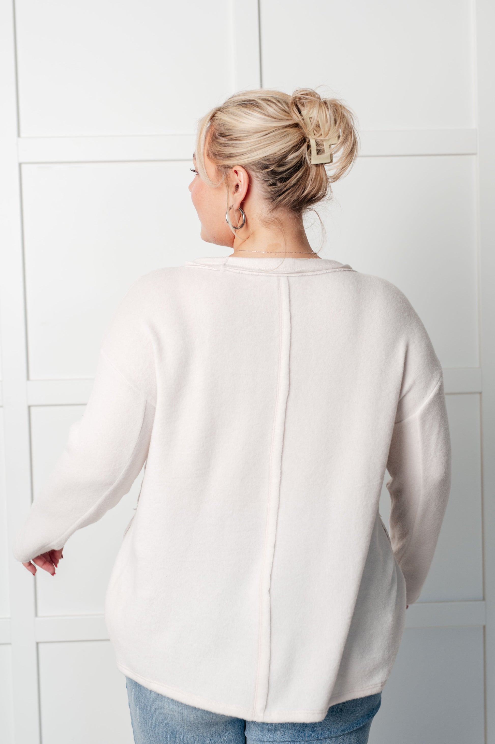 Women's Brushed Hacci Sweater in Sand Beige featuring a round neckline, drop shoulders, stepped hemline, side slits, and raw seams. 