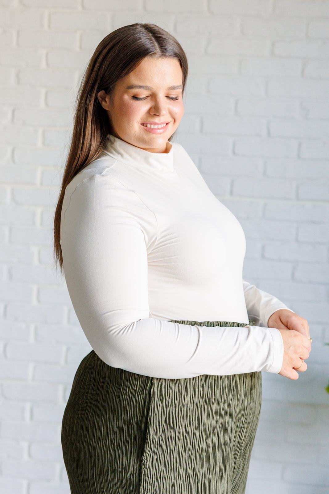 Women's bodysuit with a mock neckline, long sleeves, buttery soft double-brushed microfiber fabric, and a seamless thong bottom in White Pearl.