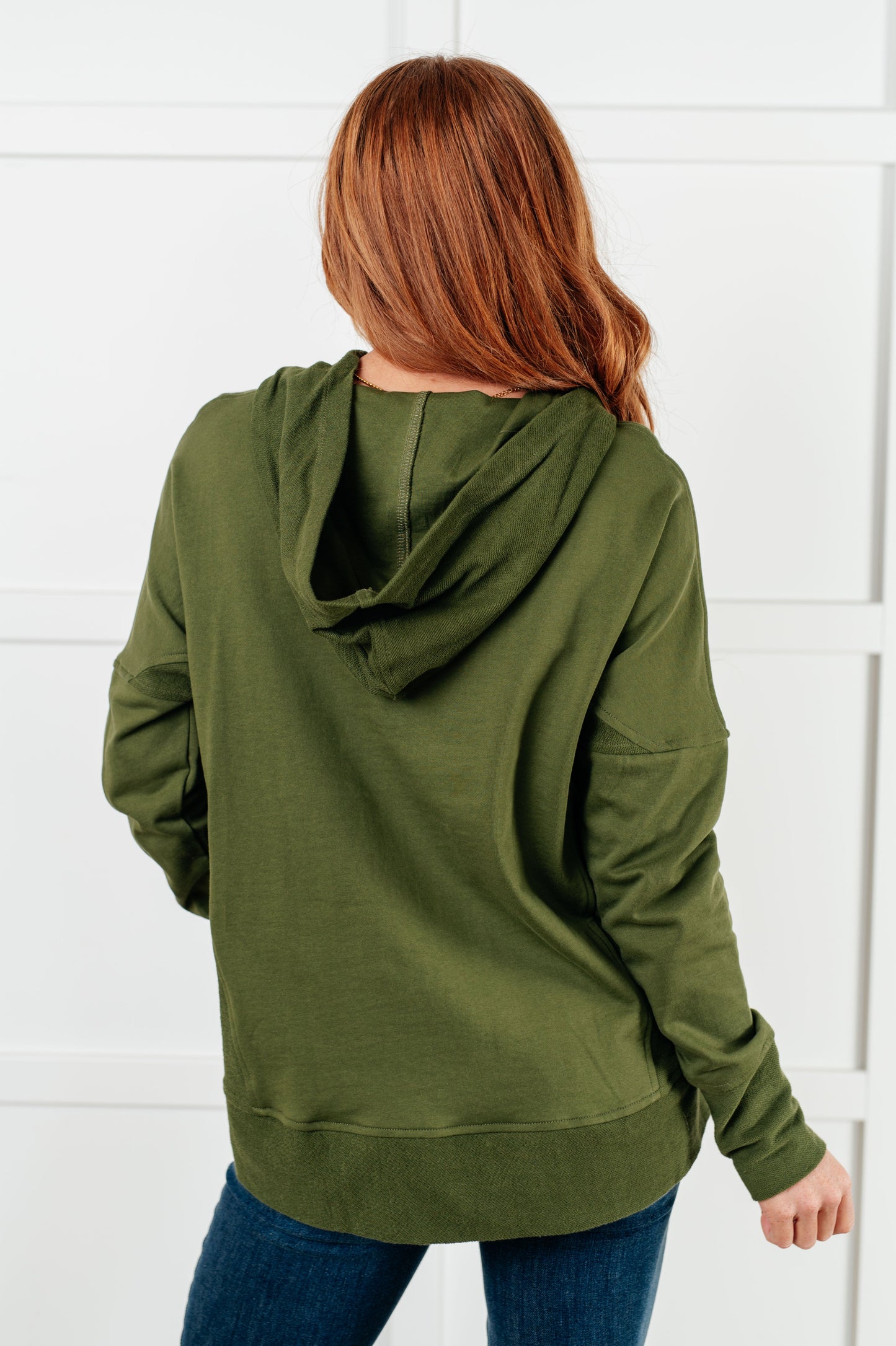 Women's green hooded pullover made with soft French Terry fabric, featuring snap button closures, long drop-shoulder sleeves with exaggerated cuffs, contrast details, and functional side pockets.