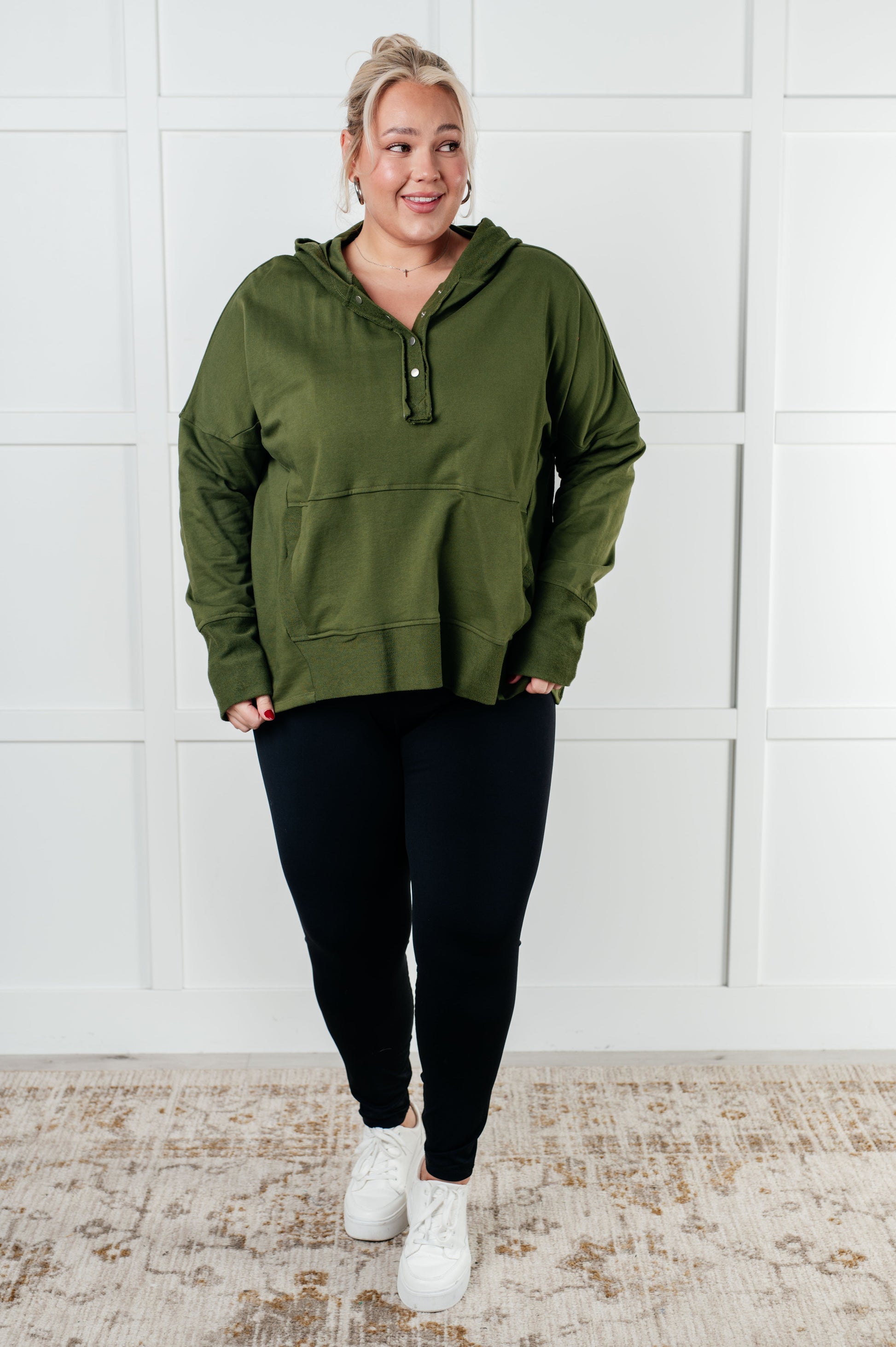 Women's green hooded pullover made with soft French Terry fabric, featuring snap button closures, long drop-shoulder sleeves with exaggerated cuffs, contrast details, and functional side pockets.