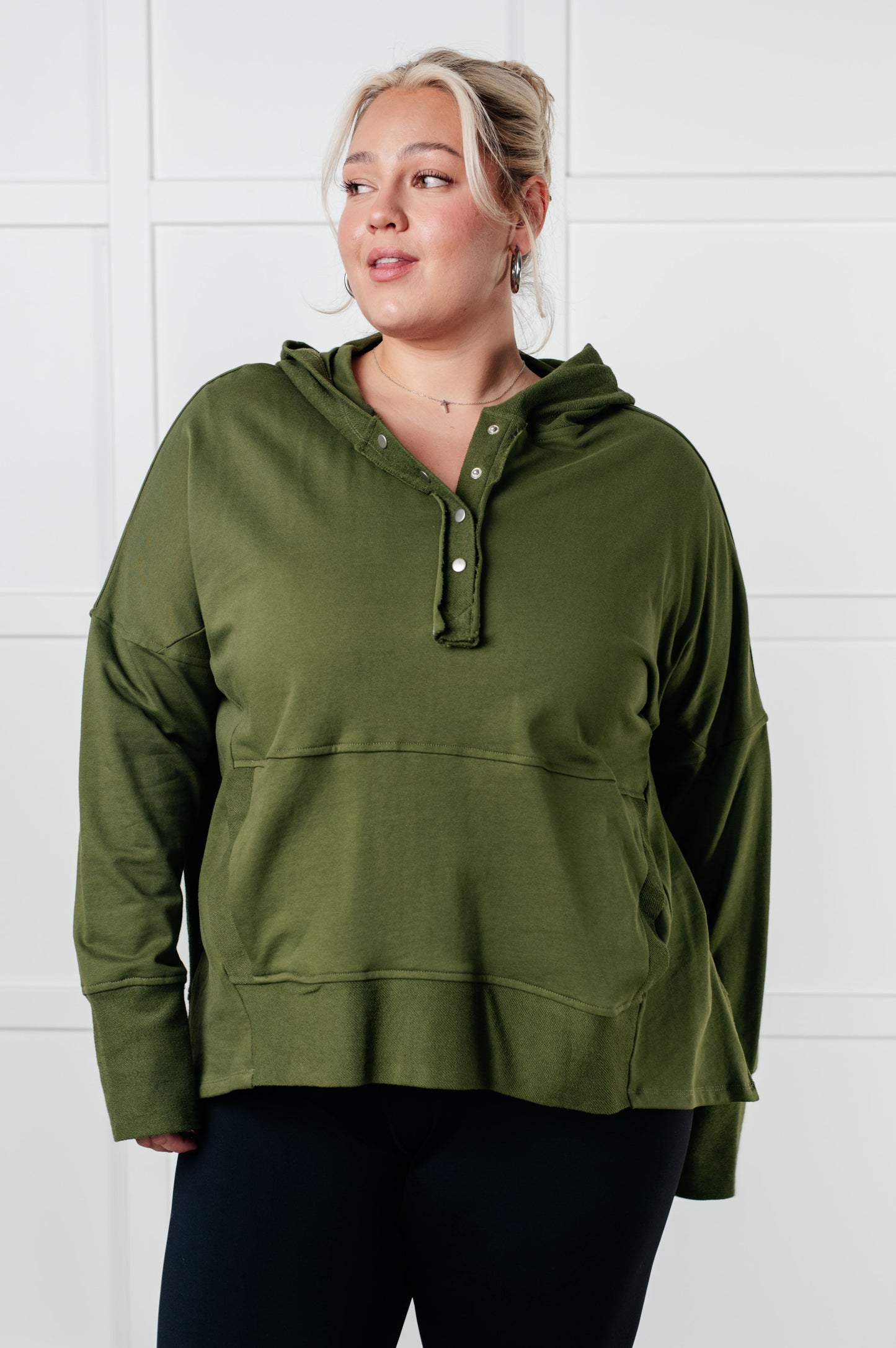 Women's green hooded pullover made with soft French Terry fabric, featuring snap button closures, long drop-shoulder sleeves with exaggerated cuffs, contrast details, and functional side pockets.