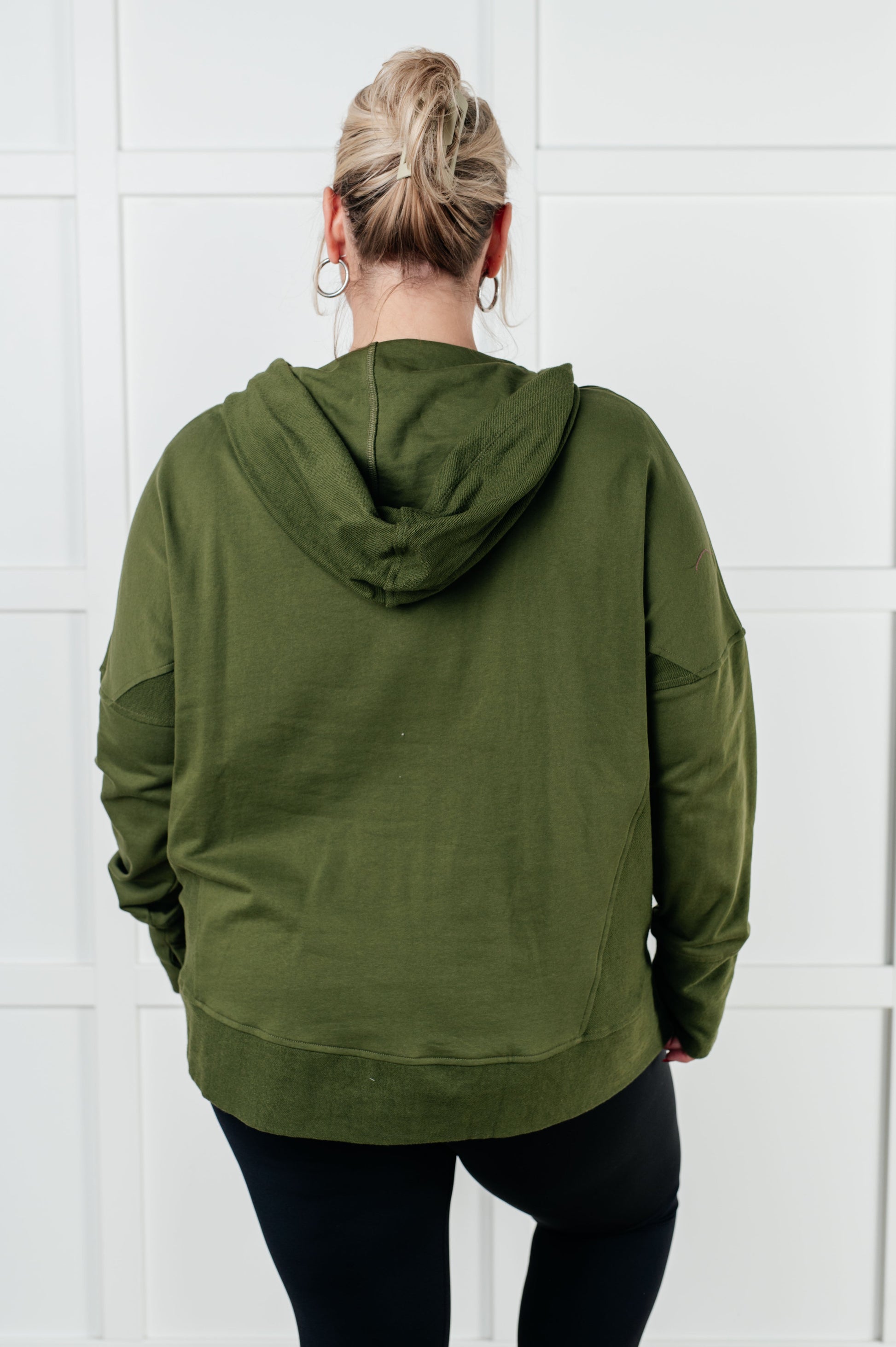 Women's green hooded pullover made with soft French Terry fabric, featuring snap button closures, long drop-shoulder sleeves with exaggerated cuffs, contrast details, and functional side pockets.