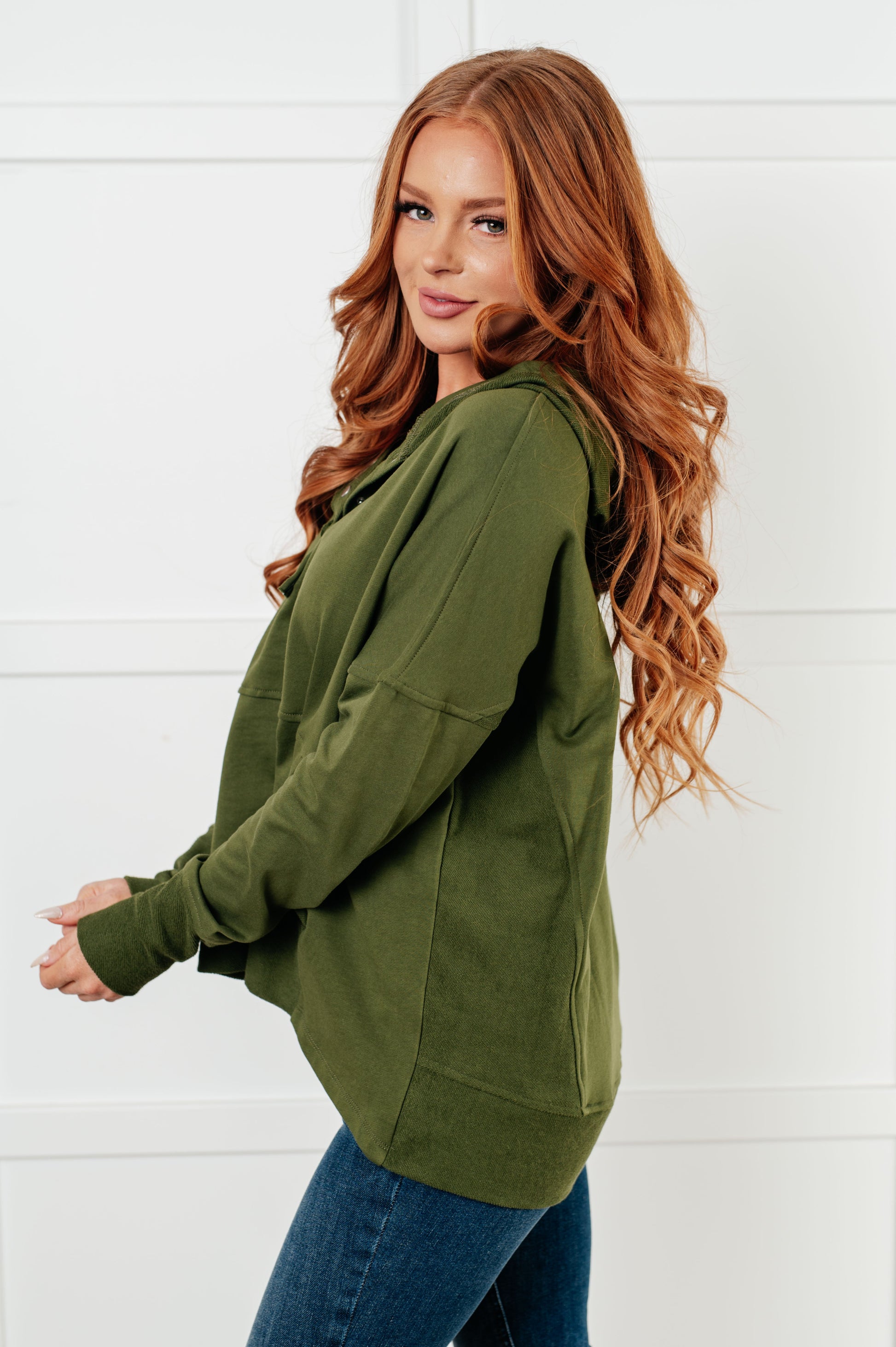 Women's green hooded pullover made with soft French Terry fabric, featuring snap button closures, long drop-shoulder sleeves with exaggerated cuffs, contrast details, and functional side pockets.