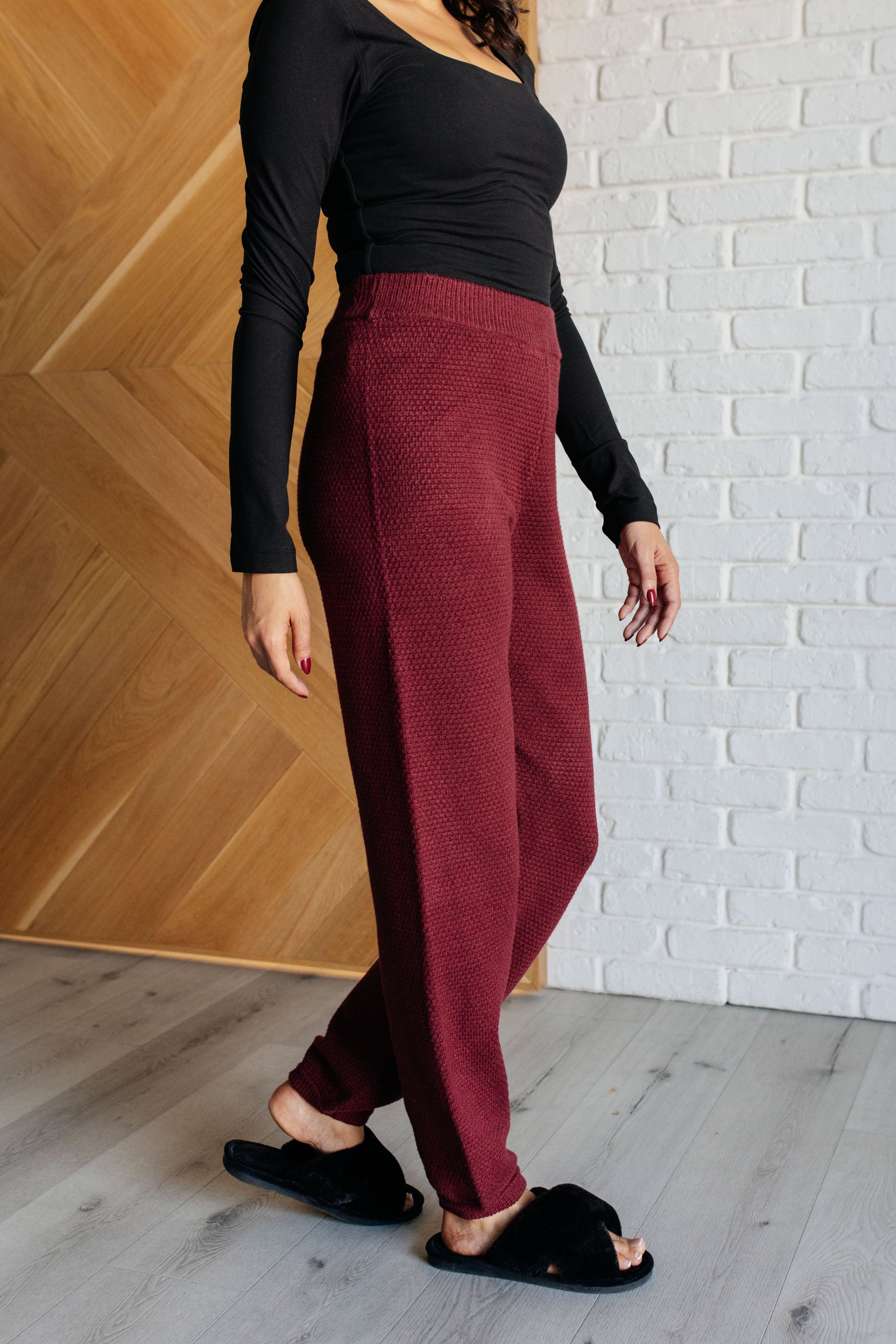 Wine-colored knit set featuring a v-neckline, button-down top with ribbed hem and sleeve cuffs, long sleeves with drop shoulders, and a high-rise jogger fit with a cased elastic ribbed waistline.