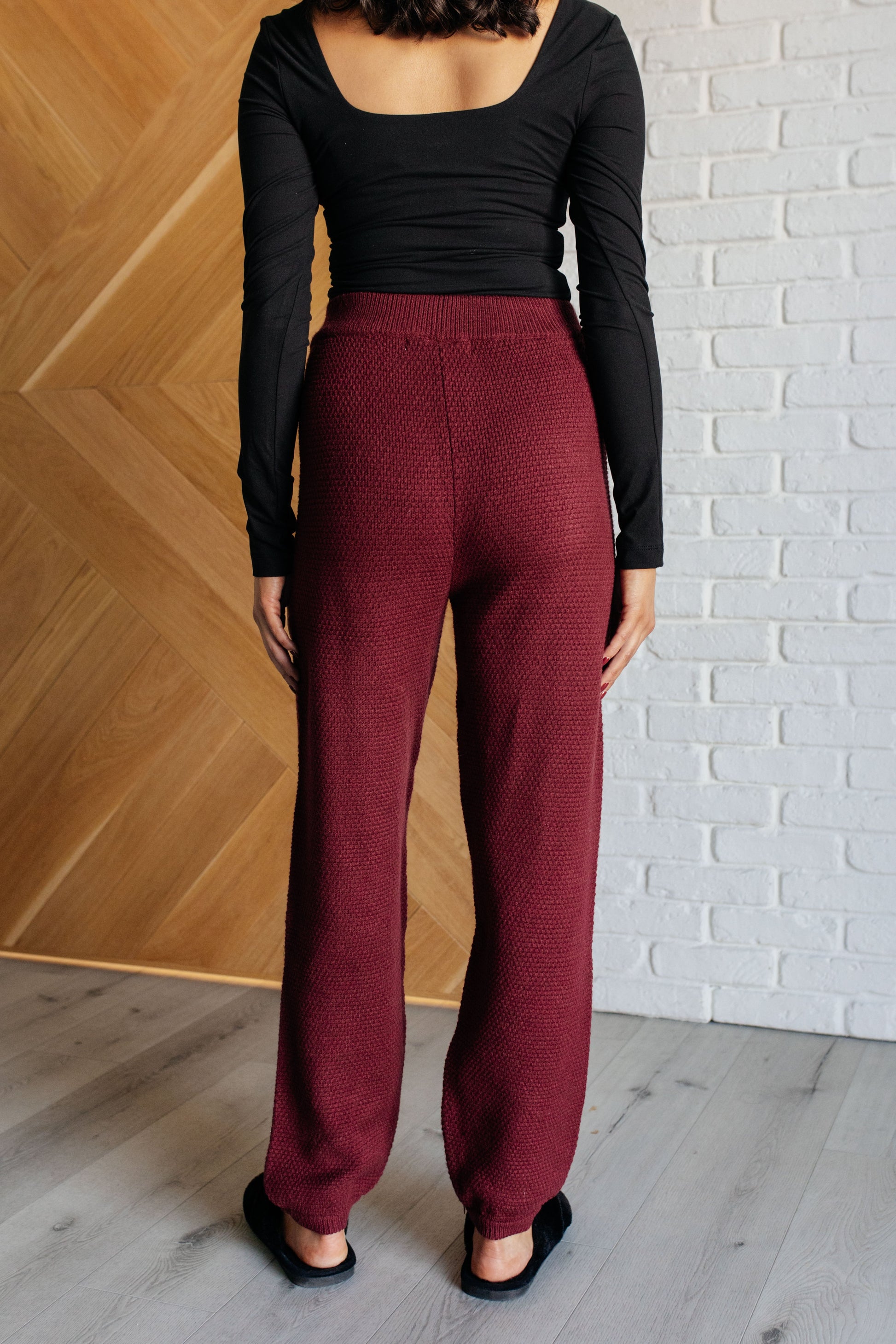 Wine-colored knit set featuring a v-neckline, button-down top with ribbed hem and sleeve cuffs, long sleeves with drop shoulders, and a high-rise jogger fit with a cased elastic ribbed waistline.