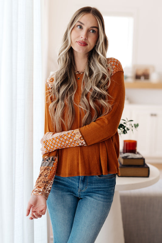 Model wearing Trissie Mixed Print Hoodie in rust, V-neck with patterned accents on hood and cuffs.