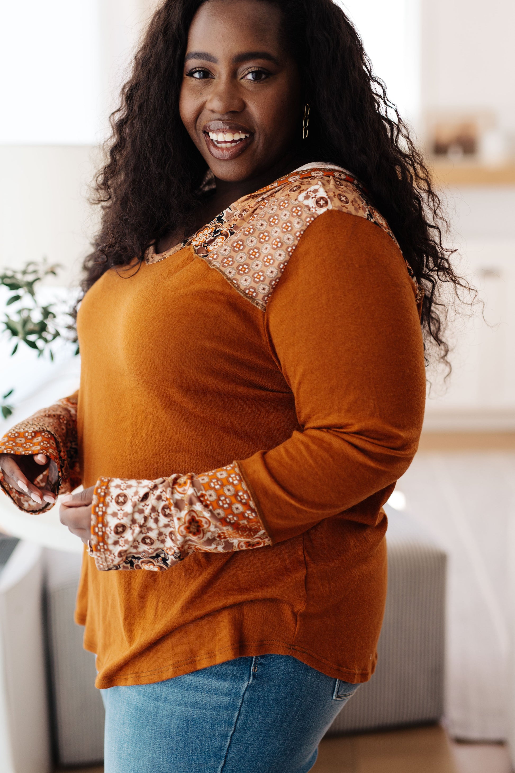 Plus-size side view of Trissie Mixed Print Hoodie, rust knit with printed accents on hood and cuffs.