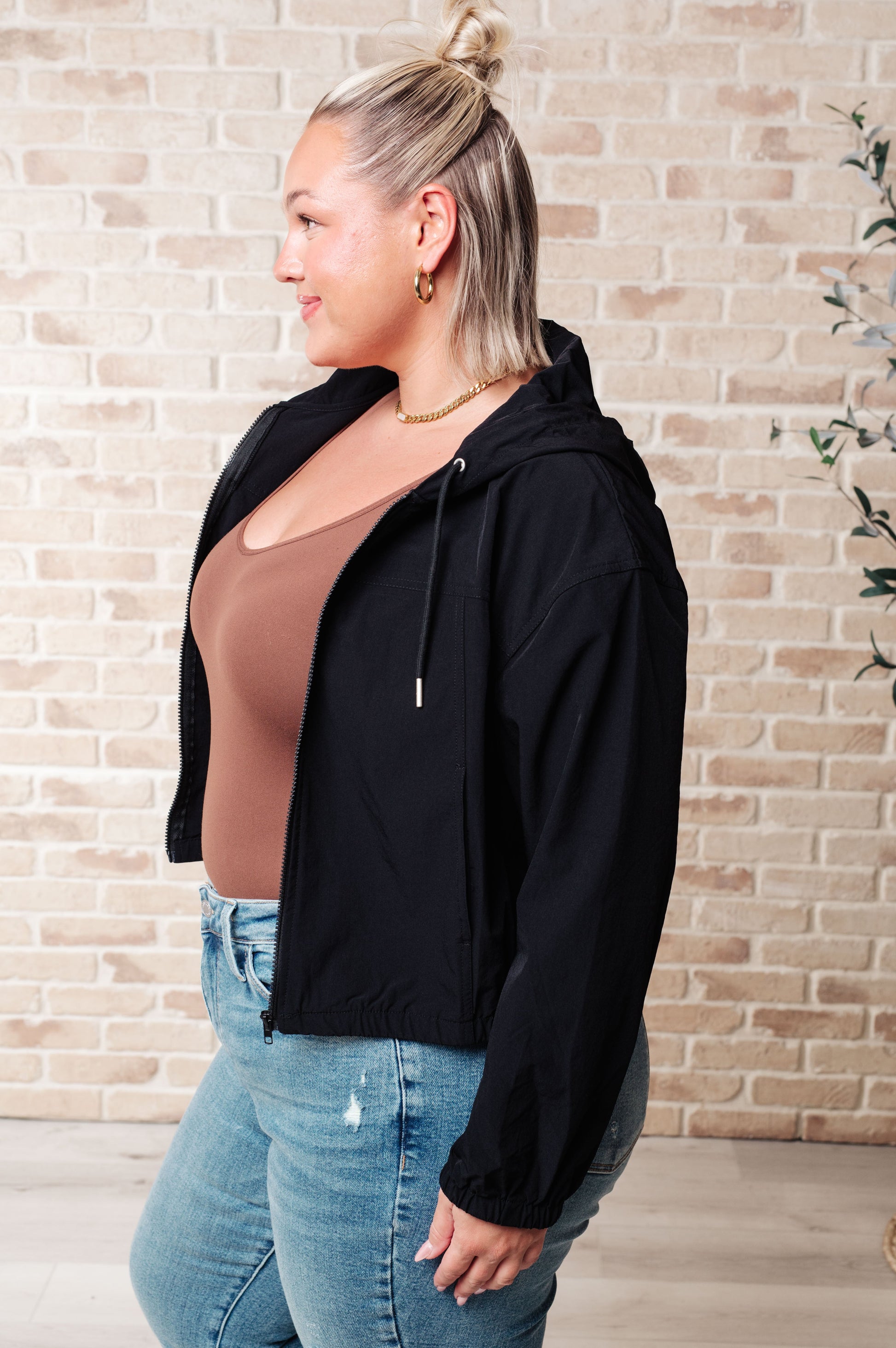 Side angle of plus size Sky Zip Up in Black highlighting relaxed fit and drawstring hood.