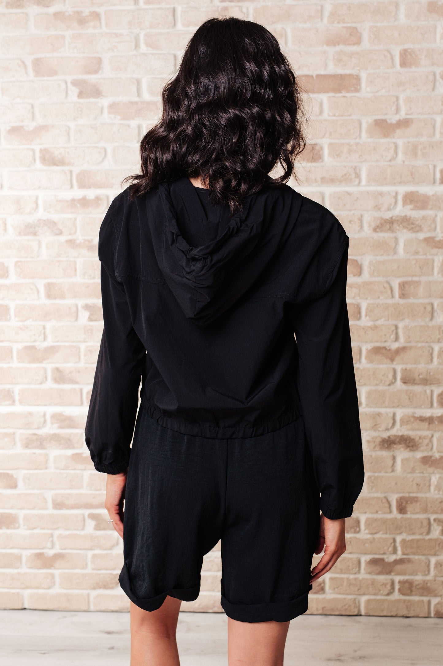 Back view of Sky Zip Up in Black featuring relaxed fit and functional hood detail.