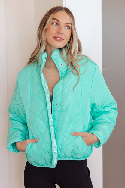 Model wearing Siyah Puffer Jacket in turquoise with mock neckline and snap front closure.