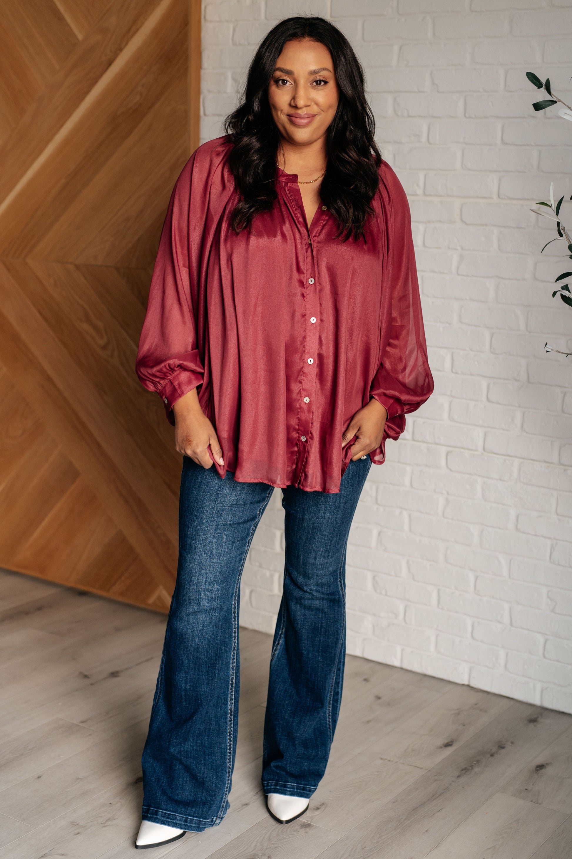 Dark plum chiffon top with a round neckline, long bat sleeves, and banded buttoned sleeve cuffs. Features a front button closure, scooped hem, and a lined bodice.