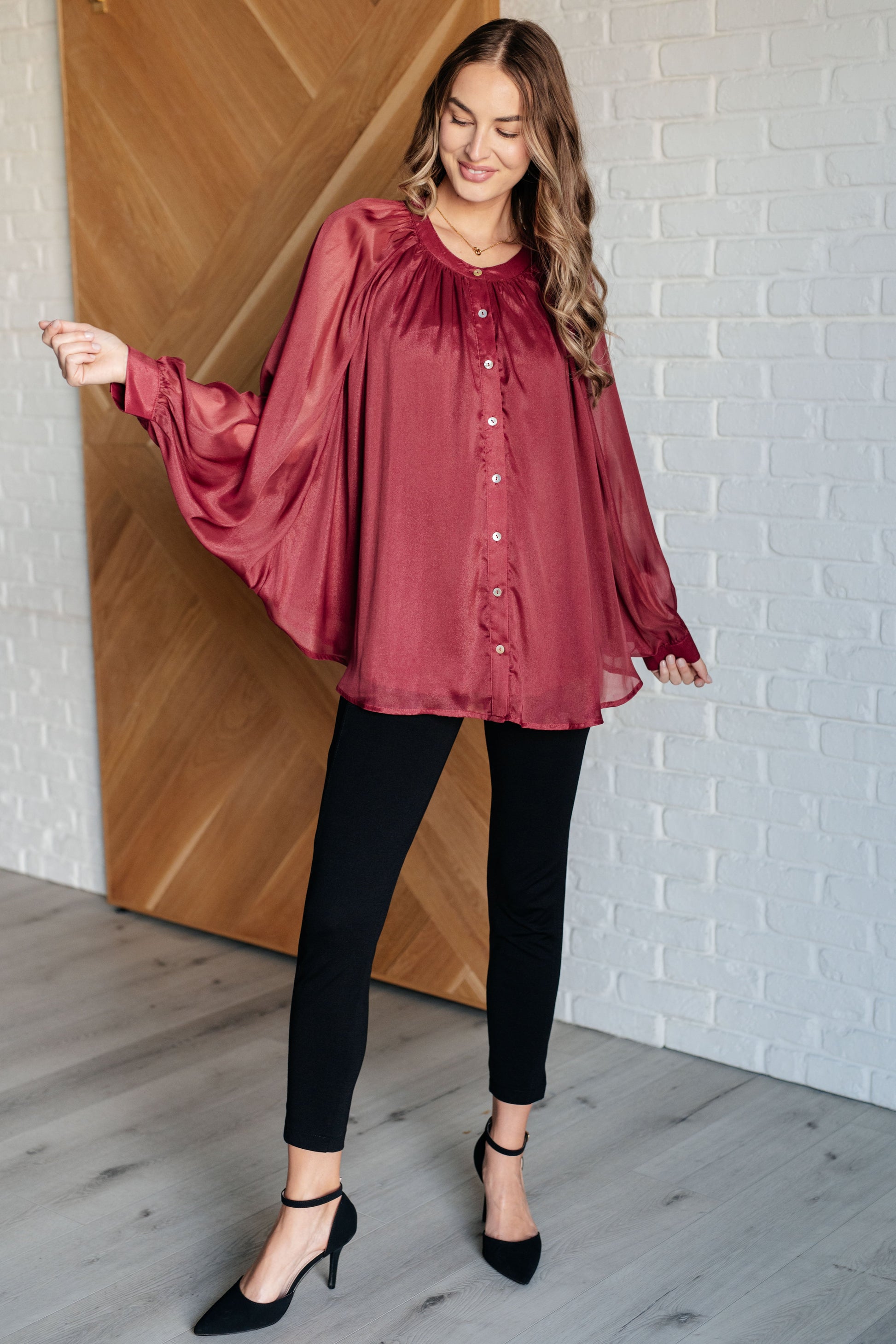 Dark plum chiffon top with a round neckline, long bat sleeves, and banded buttoned sleeve cuffs. Features a front button closure, scooped hem, and a lined bodice.