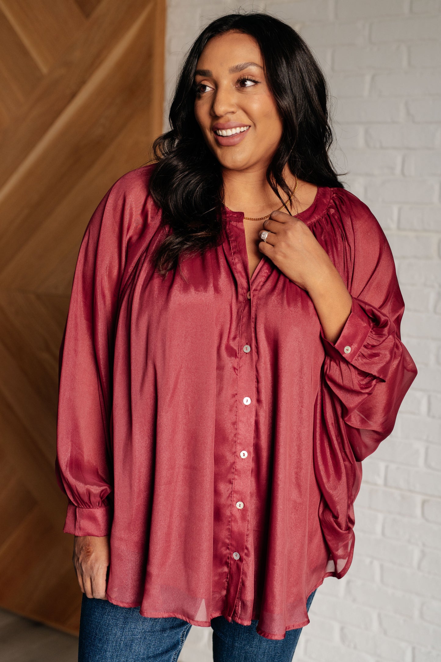 Dark plum chiffon top with a round neckline, long bat sleeves, and banded buttoned sleeve cuffs. Features a front button closure, scooped hem, and a lined bodice.