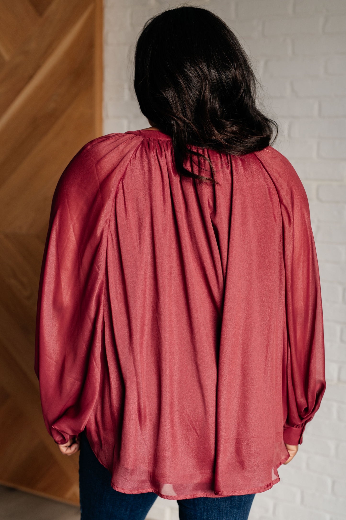 Dark plum chiffon top with a round neckline, long bat sleeves, and banded buttoned sleeve cuffs. Features a front button closure, scooped hem, and a lined bodice.