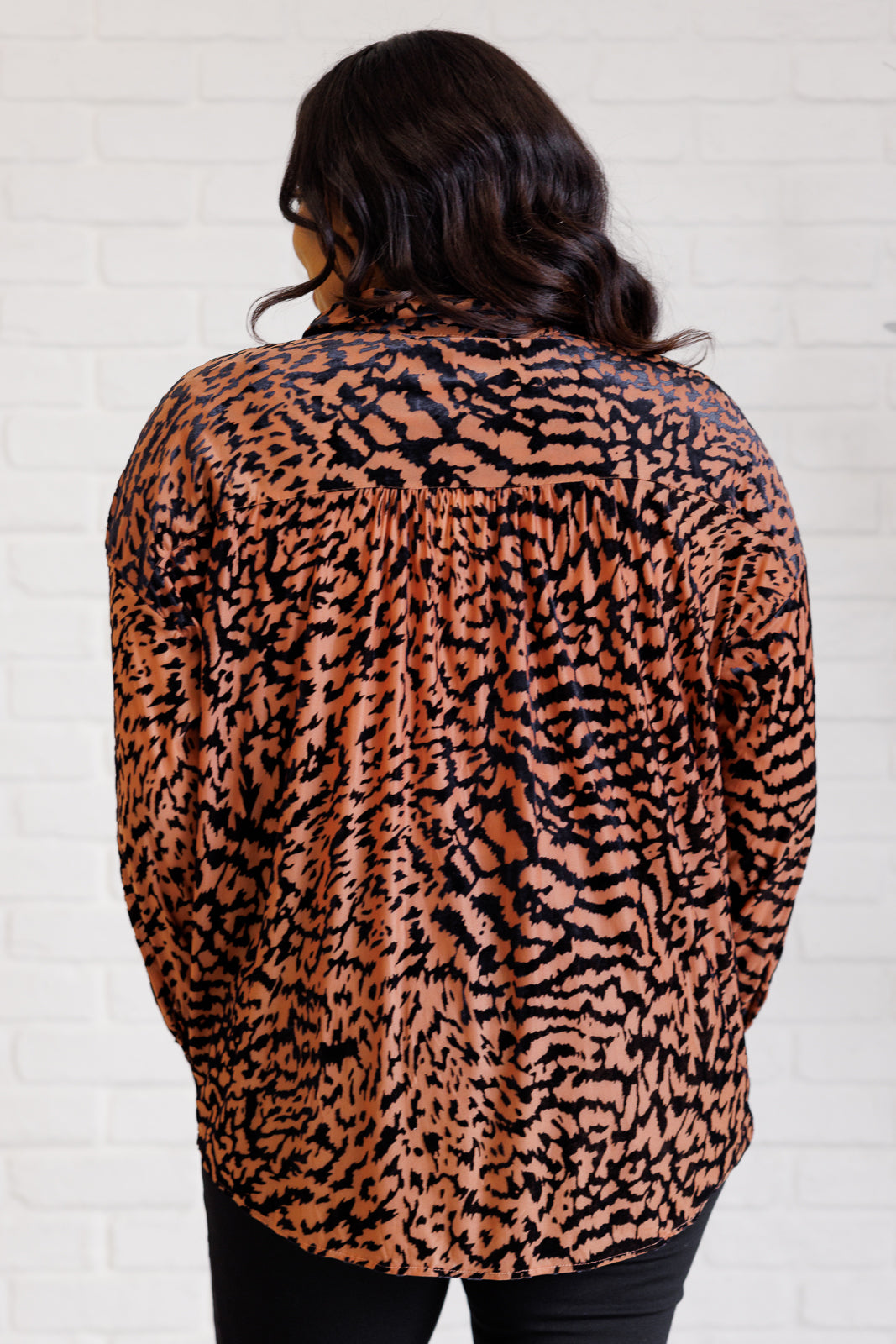 Women's blouse made of burnout velvet chiffon with an animal print design, featuring a collared neckline, long dolman sleeves, buttoned cuffs, and a button-front closure.