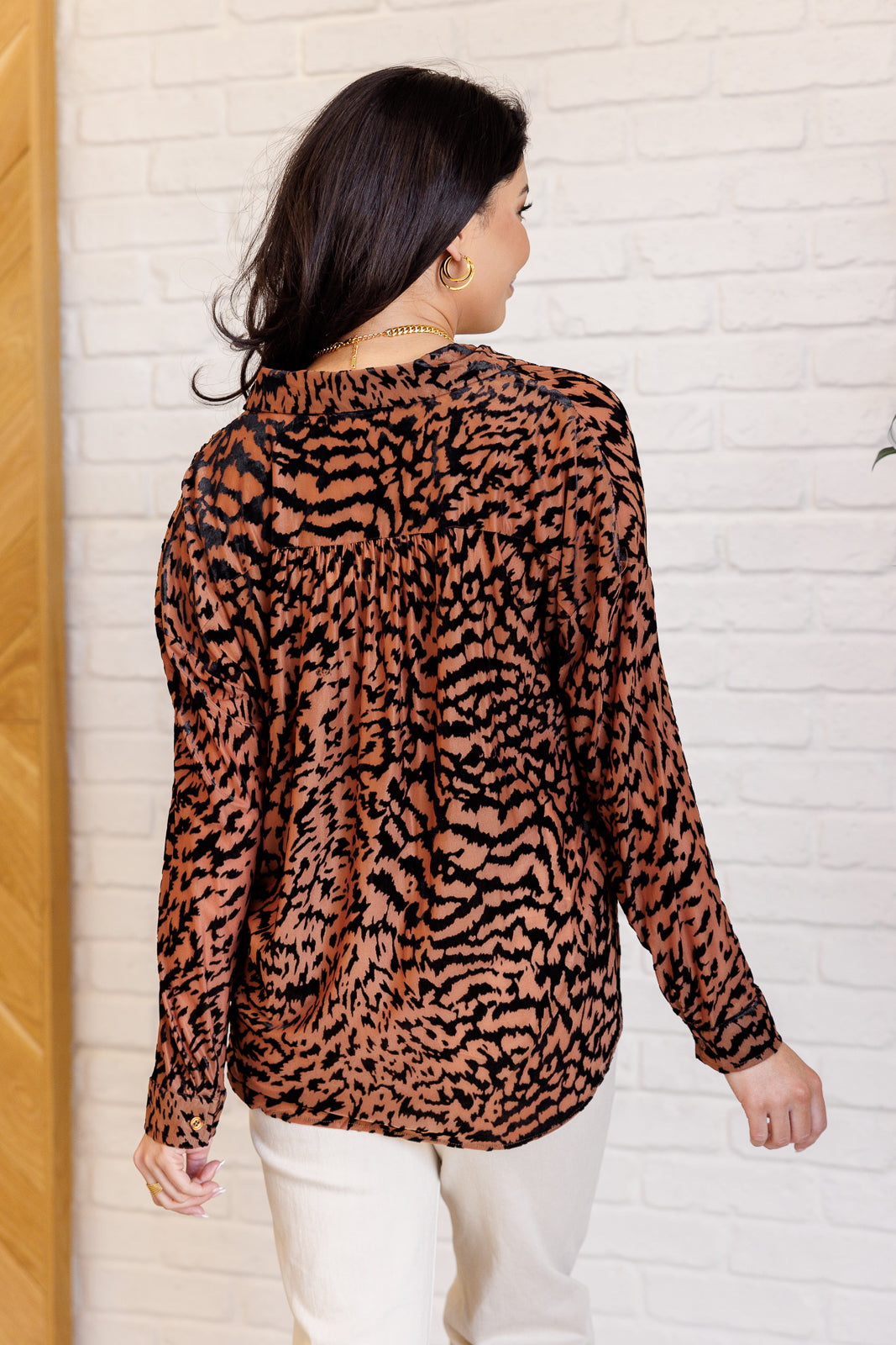 Women's blouse made of burnout velvet chiffon with an animal print design, featuring a collared neckline, long dolman sleeves, buttoned cuffs, and a button-front closure.