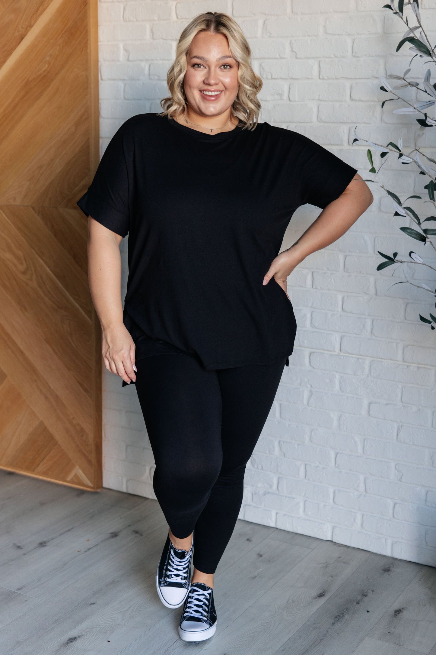 Women's black top and leggings set made with brushed microfiber. The top has a round neckline, dolman sleeves, and a high-low hemline with side slits. The leggings have a cased elastic waistline.