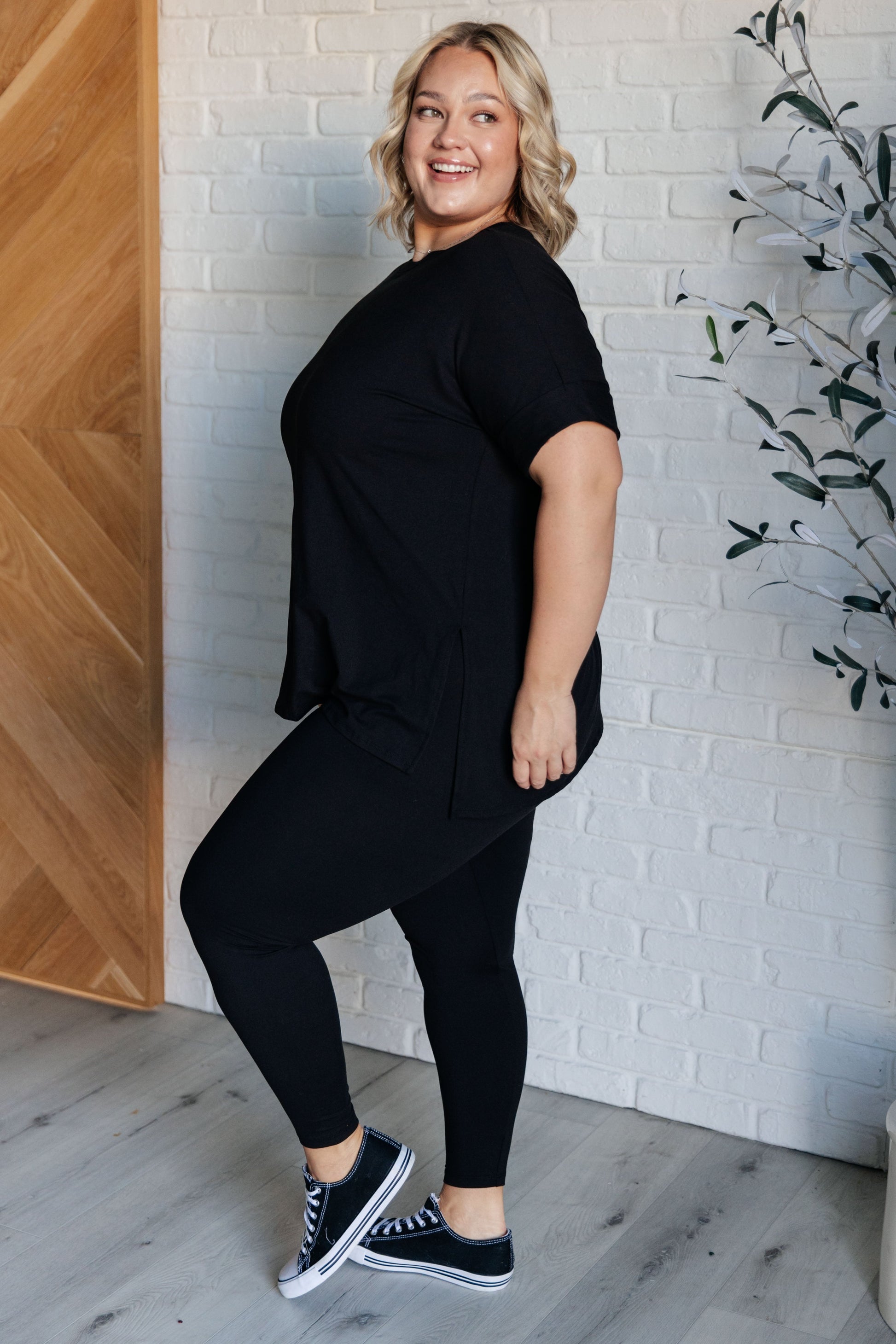 Women's black top and leggings set made with brushed microfiber. The top has a round neckline, dolman sleeves, and a high-low hemline with side slits. The leggings have a cased elastic waistline.