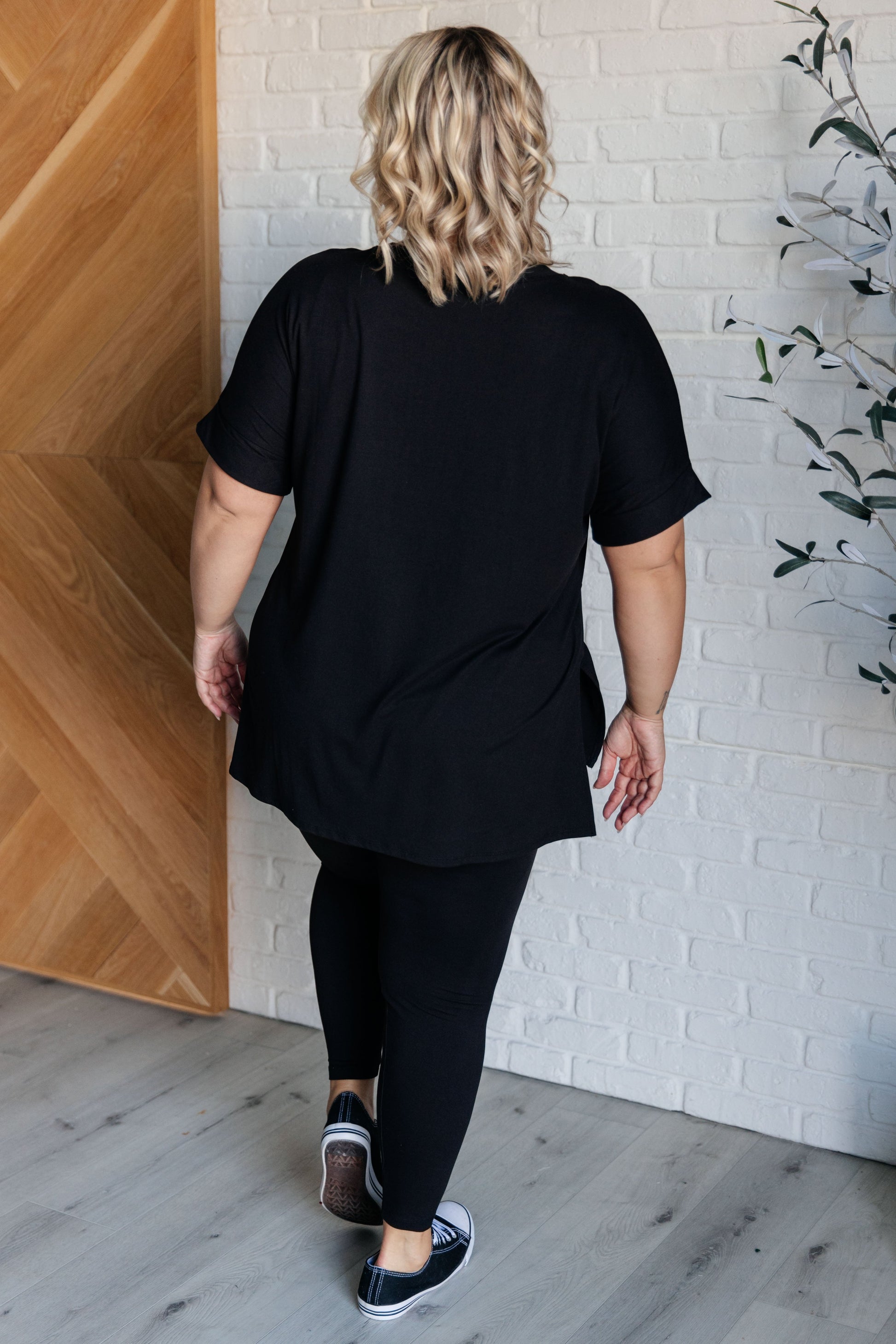 Women's black top and leggings set made with brushed microfiber. The top has a round neckline, dolman sleeves, and a high-low hemline with side slits. The leggings have a cased elastic waistline.