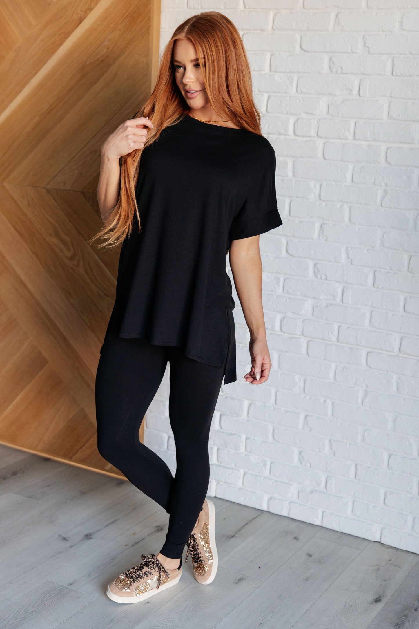 Women's black top and leggings set made with brushed microfiber. The top has a round neckline, dolman sleeves, and a high-low hemline with side slits. The leggings have a cased elastic waistline.