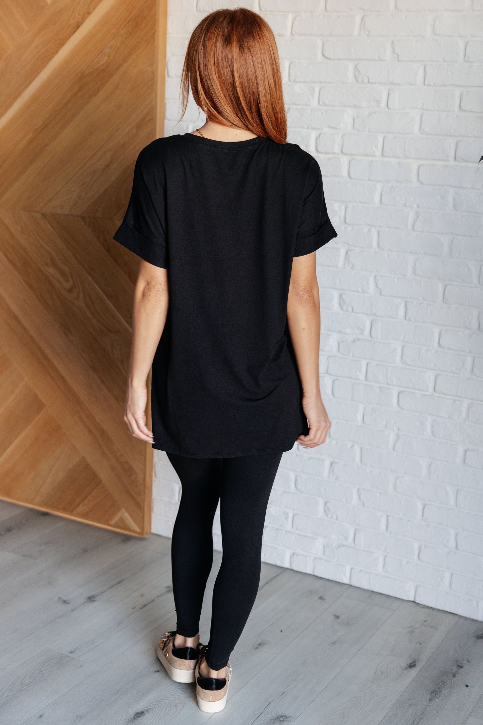 Women's black top and leggings set made with brushed microfiber. The top has a round neckline, dolman sleeves, and a high-low hemline with side slits. The leggings have a cased elastic waistline.