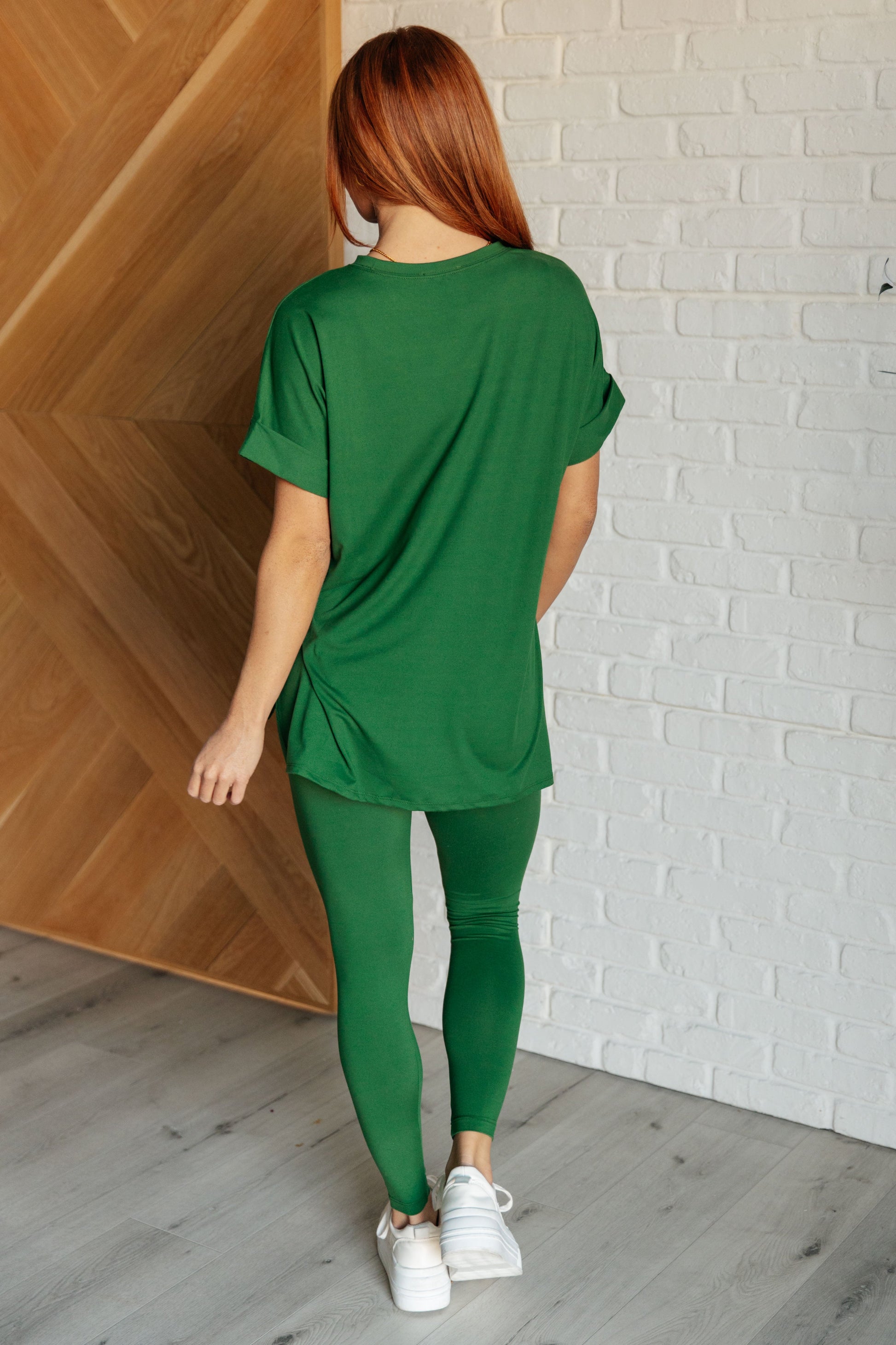 Women's dark green top and leggings set made with brushed microfiber. The top has a round neckline, dolman sleeves, and a high-low hemline with side slits. The leggings have a cased elastic waistline.