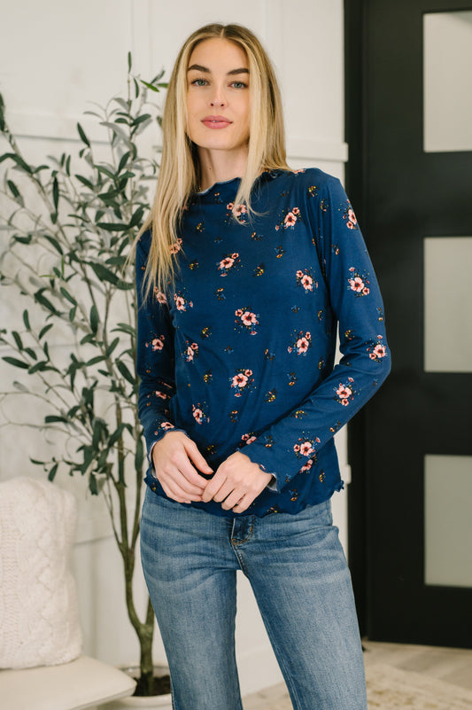 Model wearing Sondria Lettuce Hem Top in navy floral with high neckline and long sleeves.