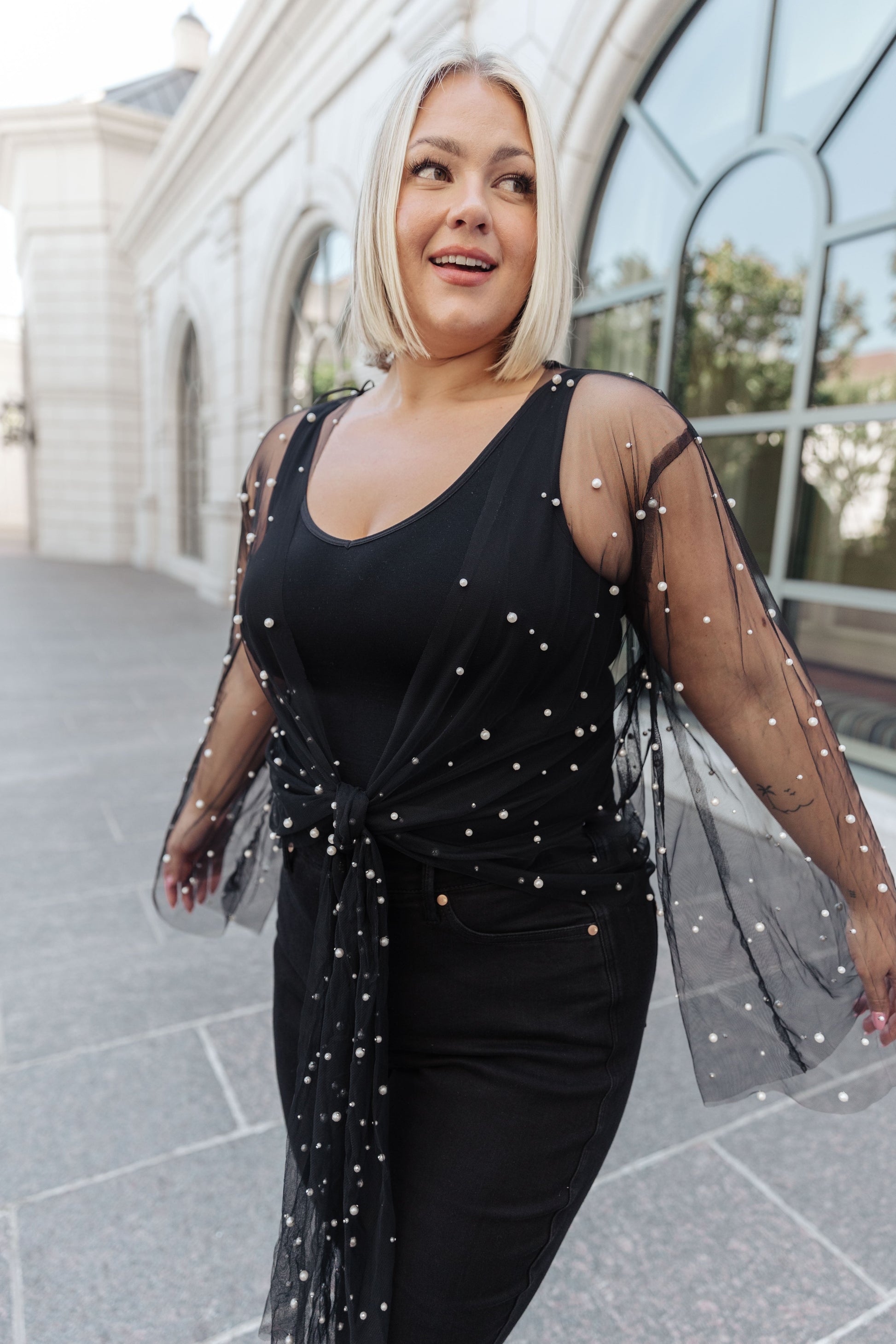 Women's sheer kimono in black mesh with faux pearl embellishments, featuring long flared sleeves, an open front, and an optional self-tie. Perfect for adding a touch of glamour to any outfit.