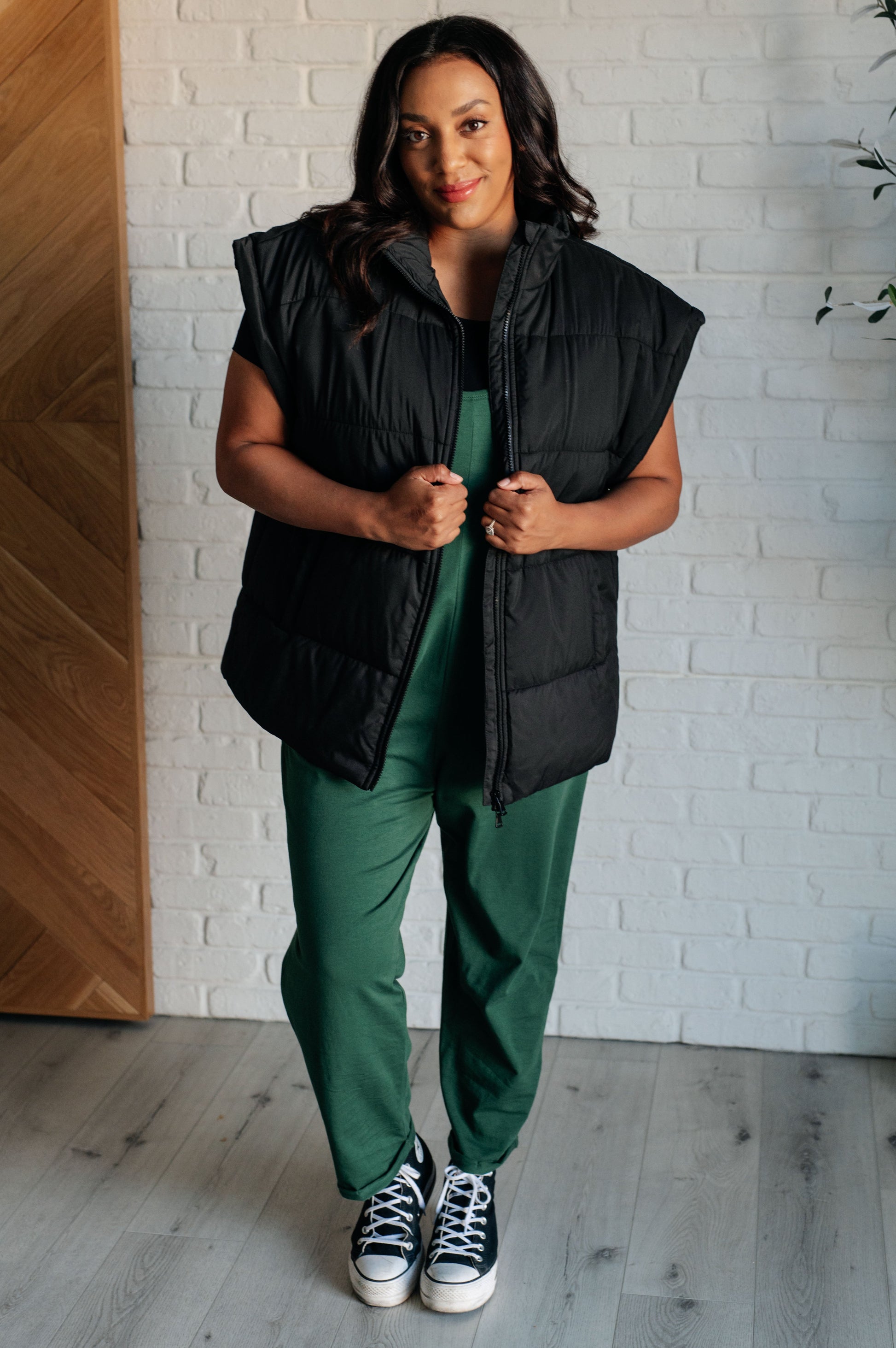 Women's black puffer vest featuring a high neckline, sleeveless design, welt pockets, and a full zipper closure for warmth and style.