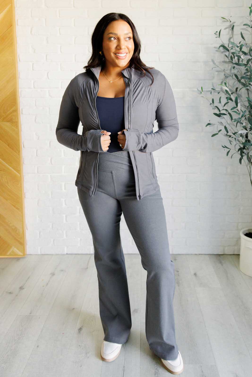 Titanium form-fitting activewear jacket with mock neckline, long sleeves, thumb holes, and a full front zipper. Features back vent and zipper pockets.