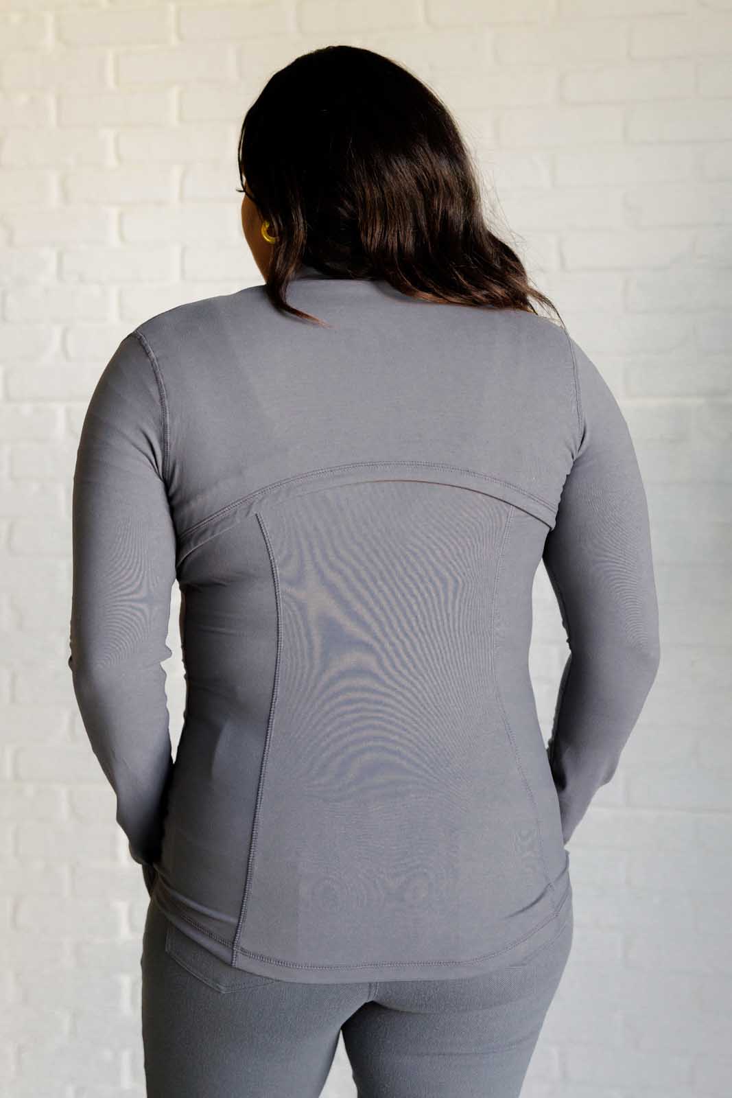 Titanium form-fitting activewear jacket with mock neckline, long sleeves, thumb holes, and a full front zipper. Features back vent and zipper pockets.