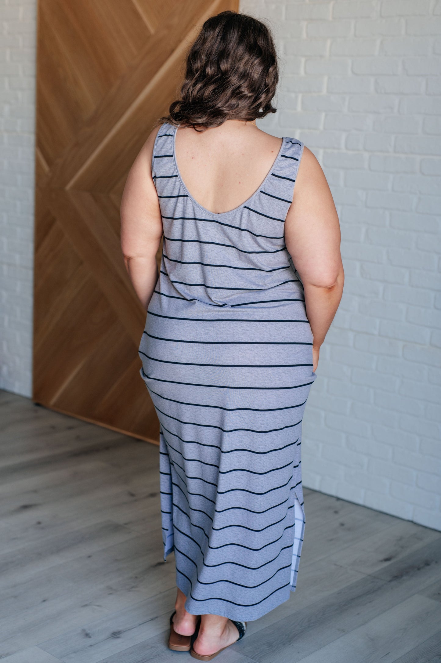 Gray striped sleeveless maxi dress made from mid-weight jersey knit, featuring a scooped neckline and side slits. 