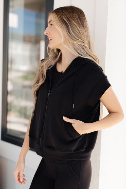 Side view of a standard-sized model wearing the Isabella Sleeveless Hoodie zipped up, with one hand in the pocket, showcasing the sleek contour seaming.