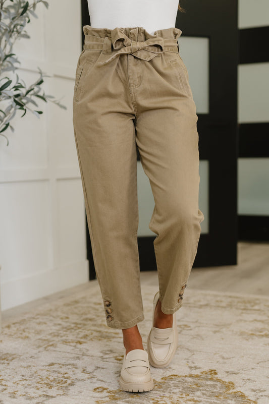 Model wearing Audie High Waist Trousers in beige with paperbag waist and detachable tie belt.