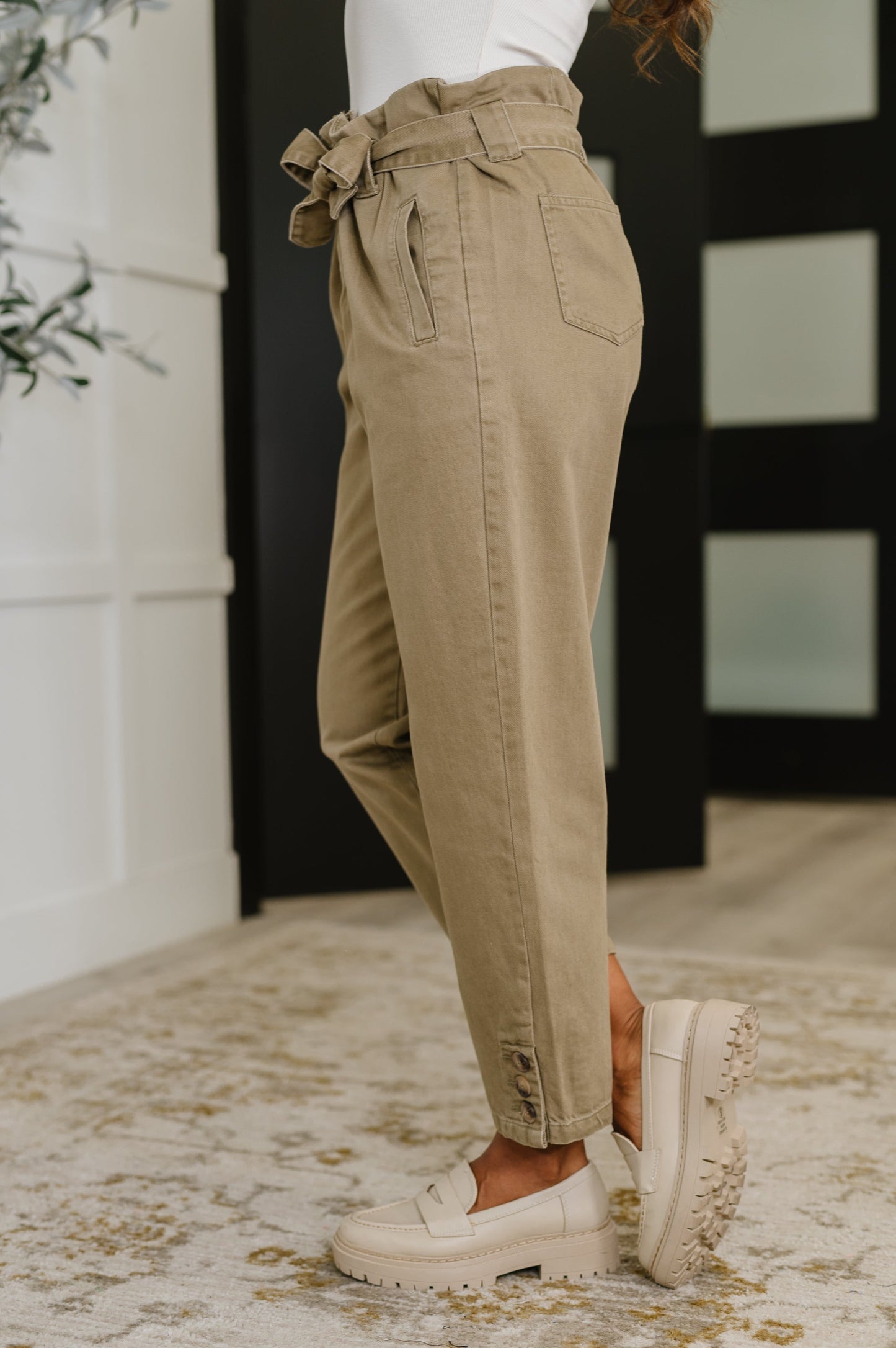 Side profile of Audie High Waist Trousers with relaxed leg and ankle button detail.