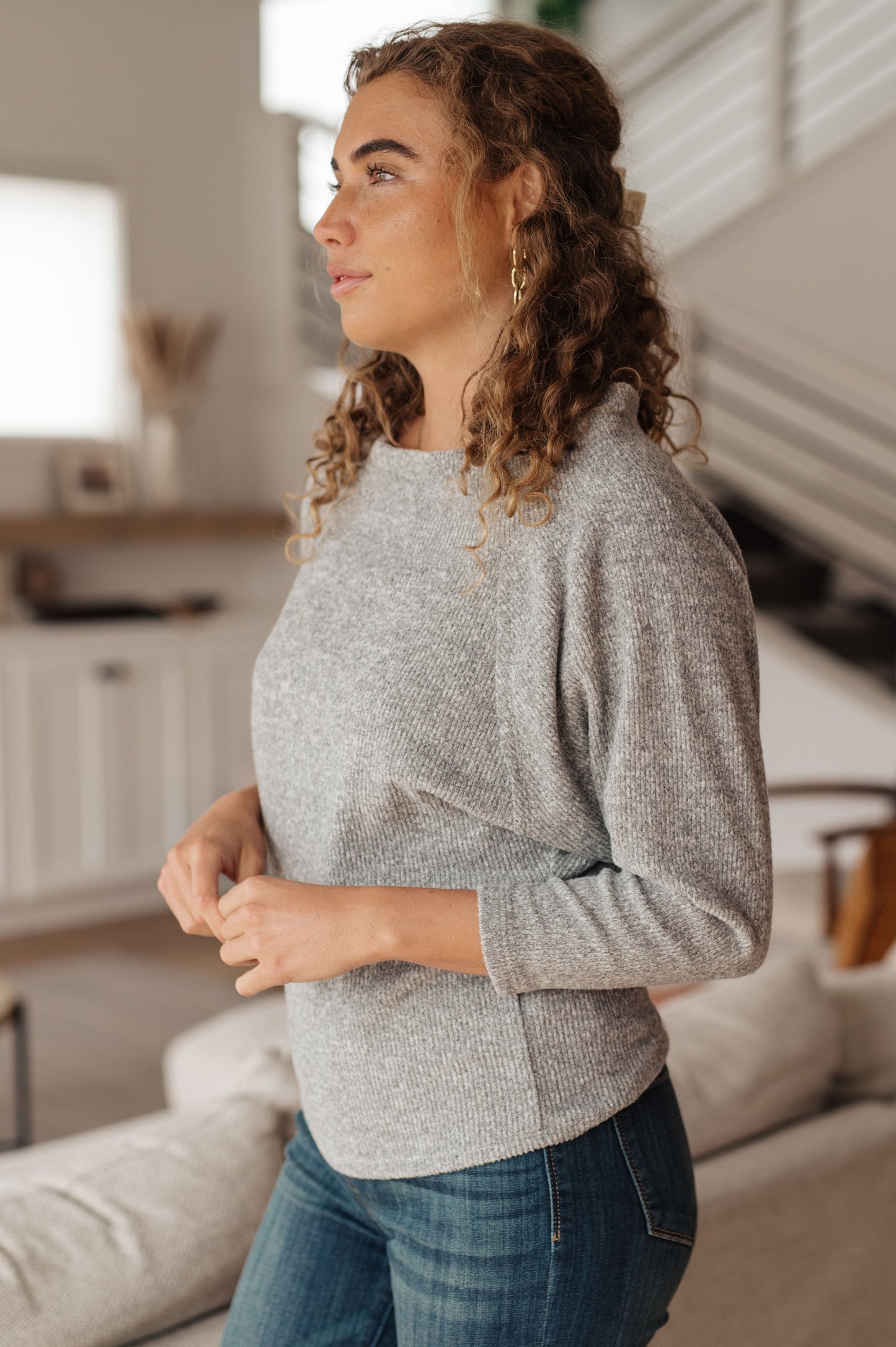 Light gray textured knit top features a boat neckline, and dolman sleeves.