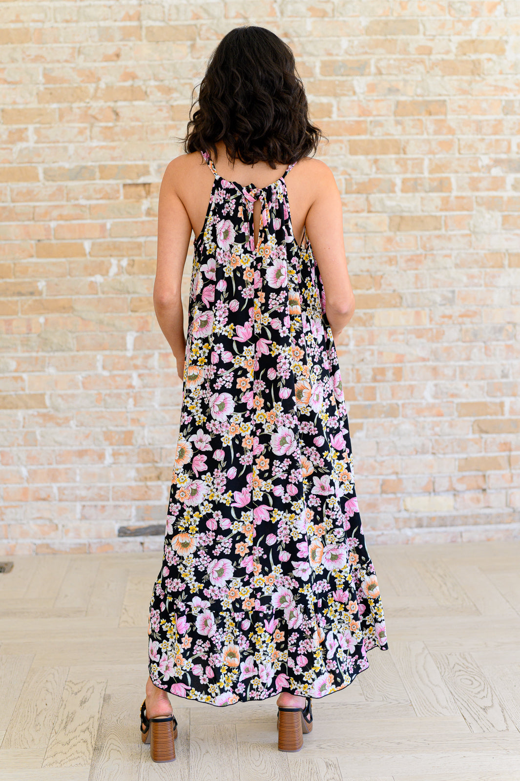 Back view of Samantha Halter Dress in black floral highlighting halter tie and flowy ruffled hem.